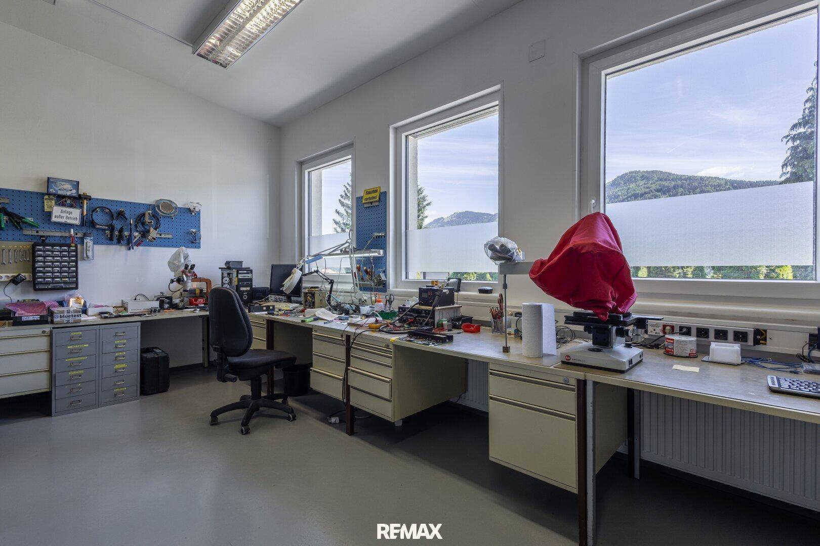 Gut ausgestatteter Werkstattraum mit großen Fenstern und Arbeitsflächen.