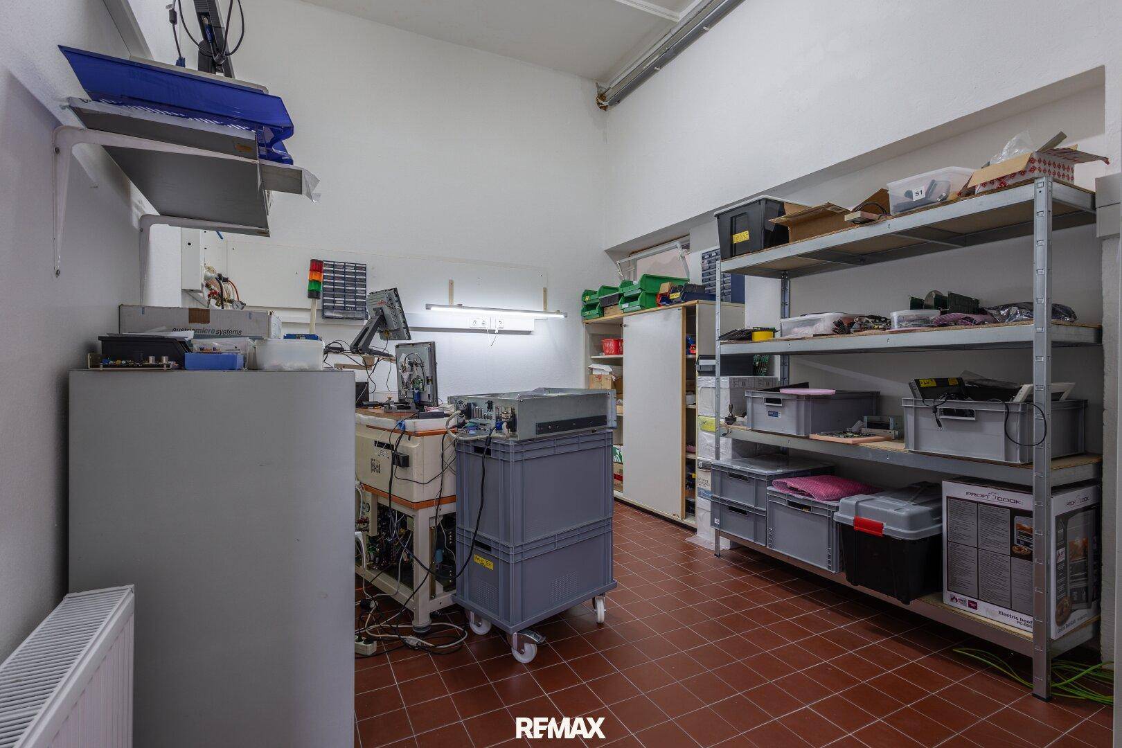 Technischer Raum mit Regalsystemen und Arbeitsplätzen für elektronische Geräte und Lagerung.