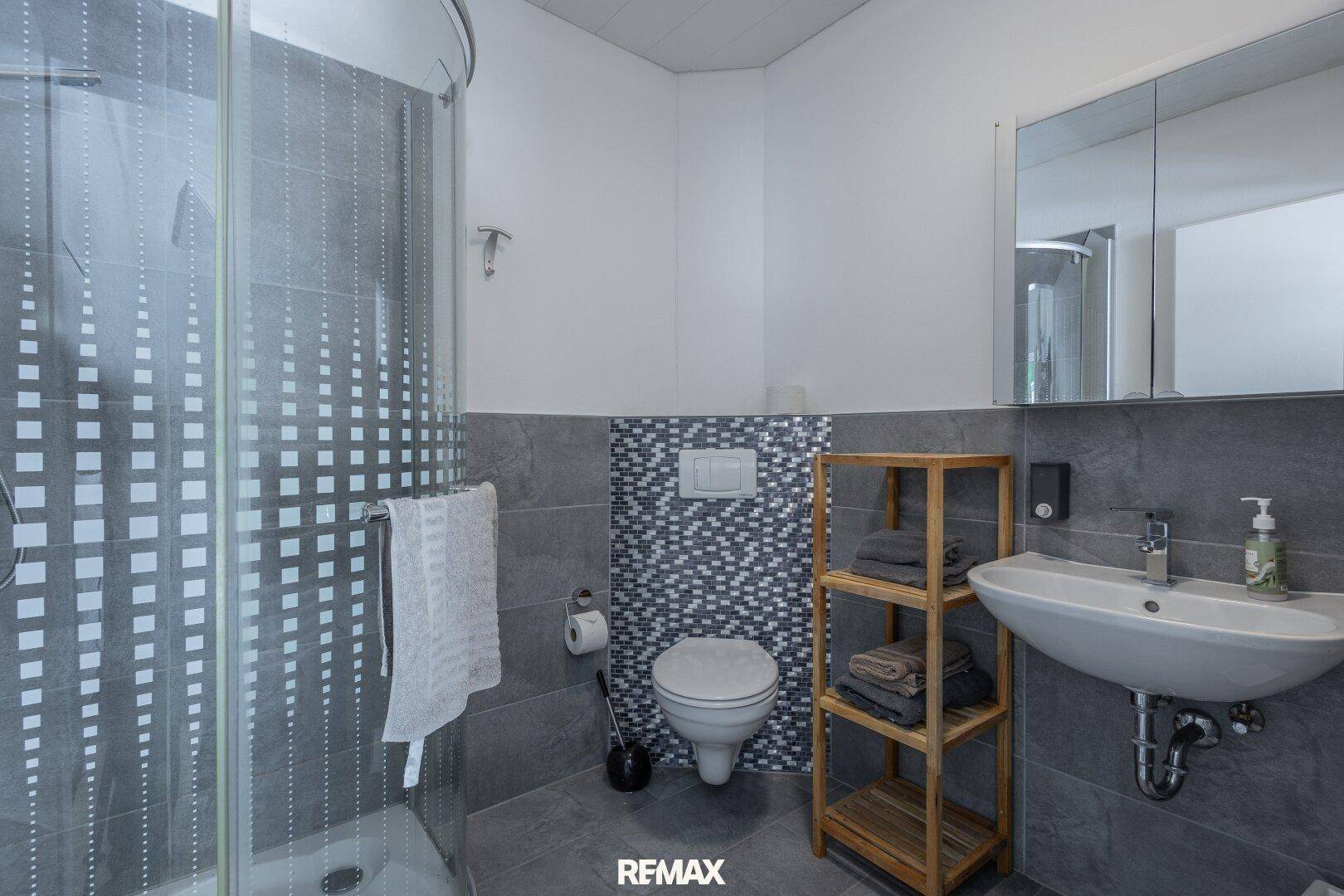 Modernes Badezimmer mit Dusche, WC und Waschbecken.