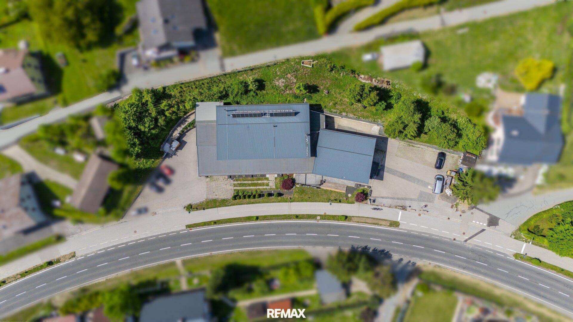Vogelperspektive des Gebäudekomplexes mit Parkplätzen und umliegender grüner Landschaft.