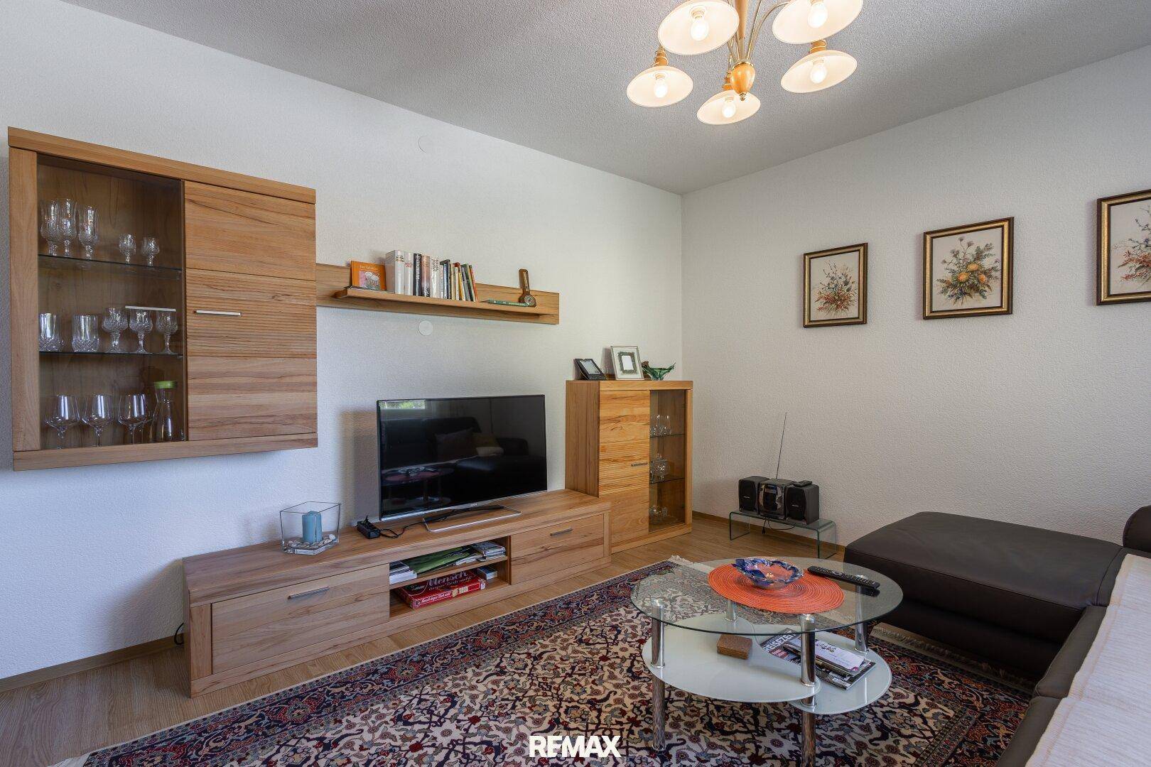 Gemütliches Wohnzimmer mit Holzboden, Teppich und modernen Holzmöbeln.