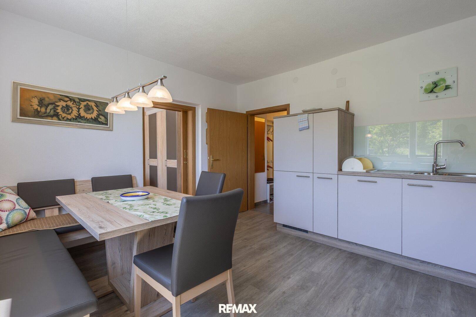 Heller Essbereich in der Küche mit Holztisch und Sitzbank, angrenzend an weitere Räume.