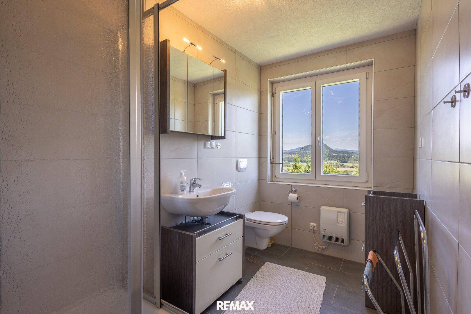 Helles Badezimmer im Dachgeschoss mit Dusche, WC und Fenster mit Bergblick.