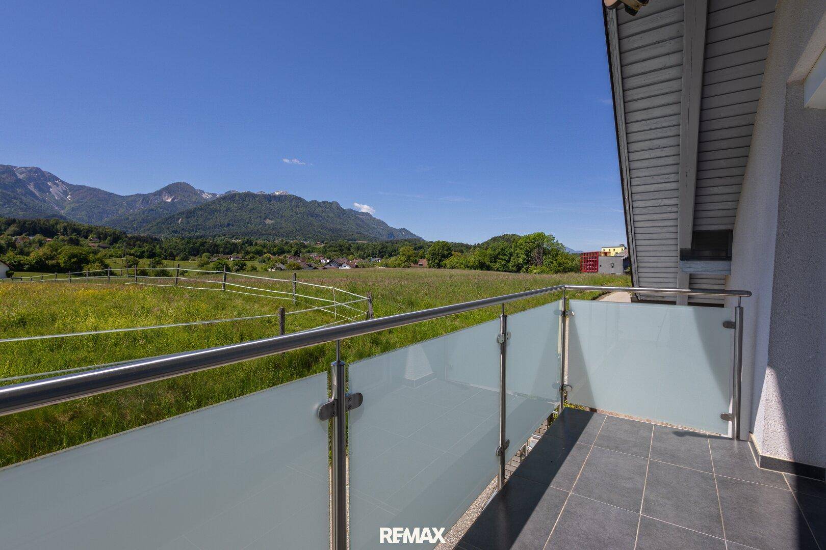 Balkon mit Glasbrüstung und Panoramablick auf die umliegende Natur und die Berglandschaft.