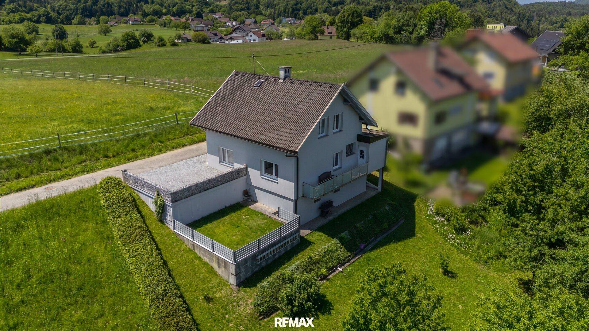 Rückansicht des Hauses mit kleinem Gartenbereich und weitem Blick über grüne Felder.