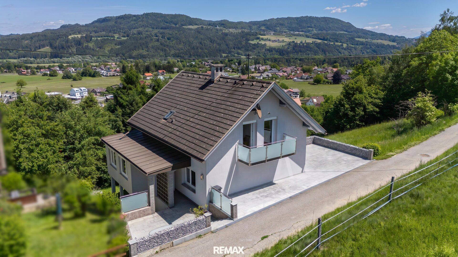 Luftaufnahme eines Einfamilienhauses mit Satteldach und Balkonen in ländlicher Umgebung.