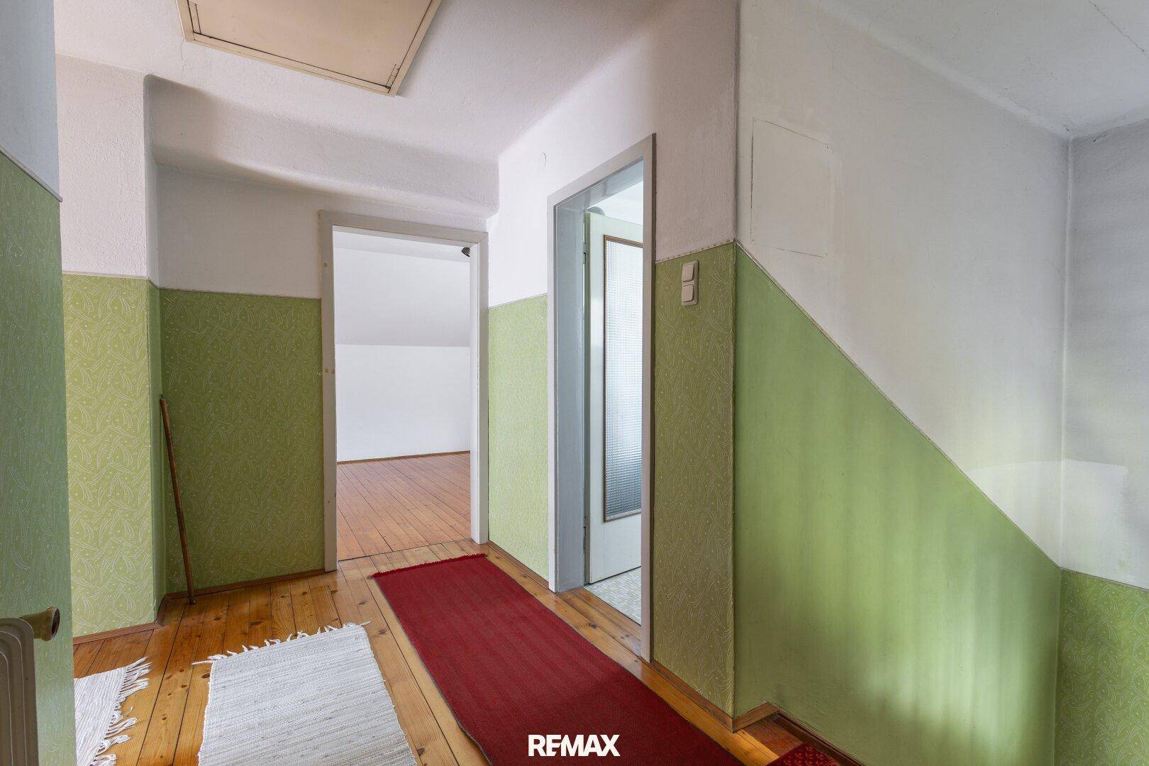 Oberer Flur mit Holztreppe, Holzboden und Blick in weitere Zimmer.