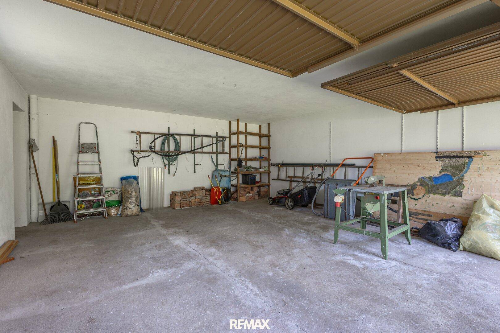 Geräumige Garage mit Werkzeugen, Leitern und Stauraum für Gartengeräte.