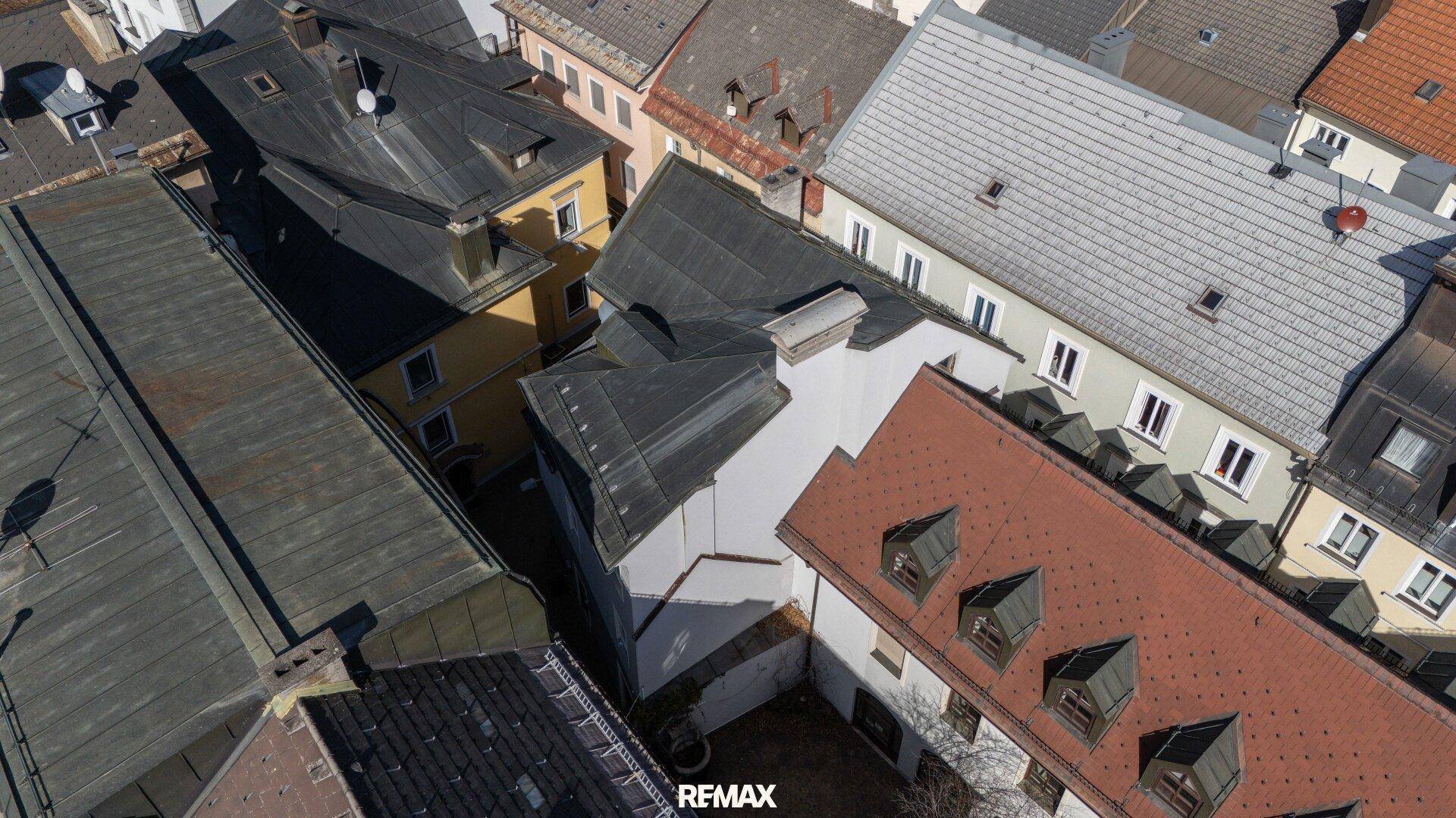 Luftaufnahme einer Ansammlung von Gebäuden und Dächern in einer dicht bebauten Stadtlandschaft.
