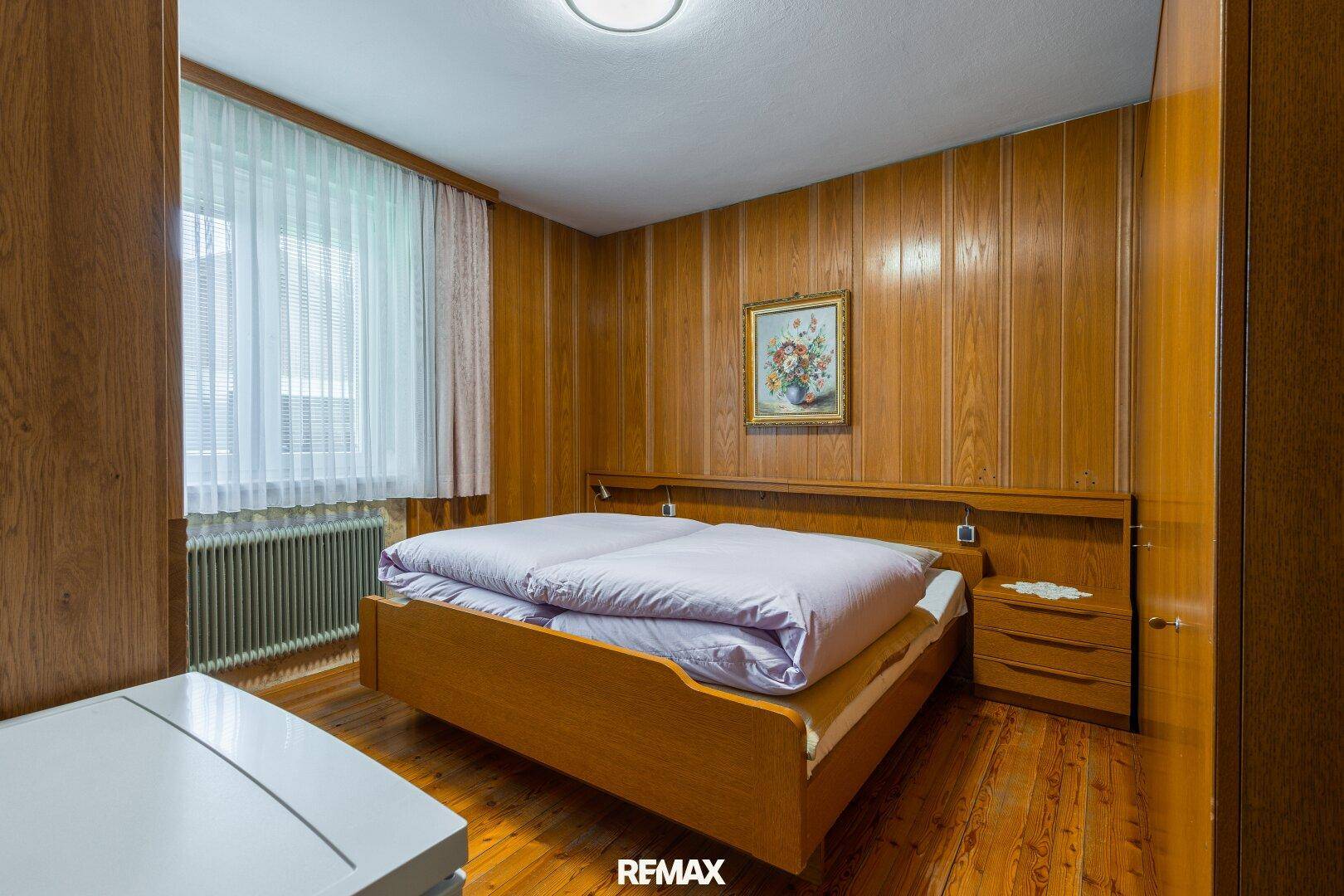Schlafzimmer mit Holzvertäfelung, Holzboden und einem Doppelbett, das eine gemütliche Atmosphäre schafft.