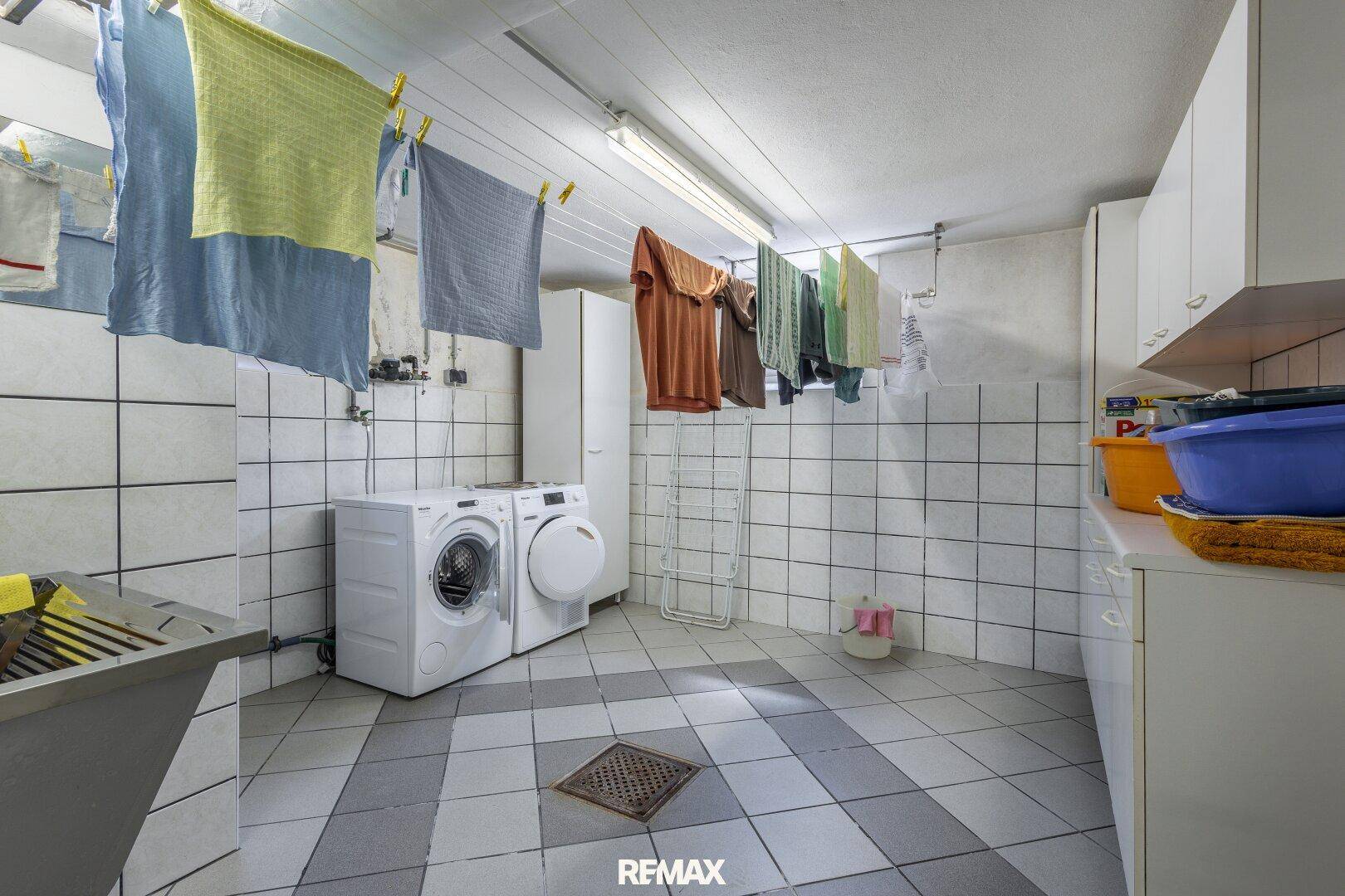 Geräumiger Hauswirtschaftsraum mit Waschmaschine, Trockner und viel Platz zum Wäschetrocknen.