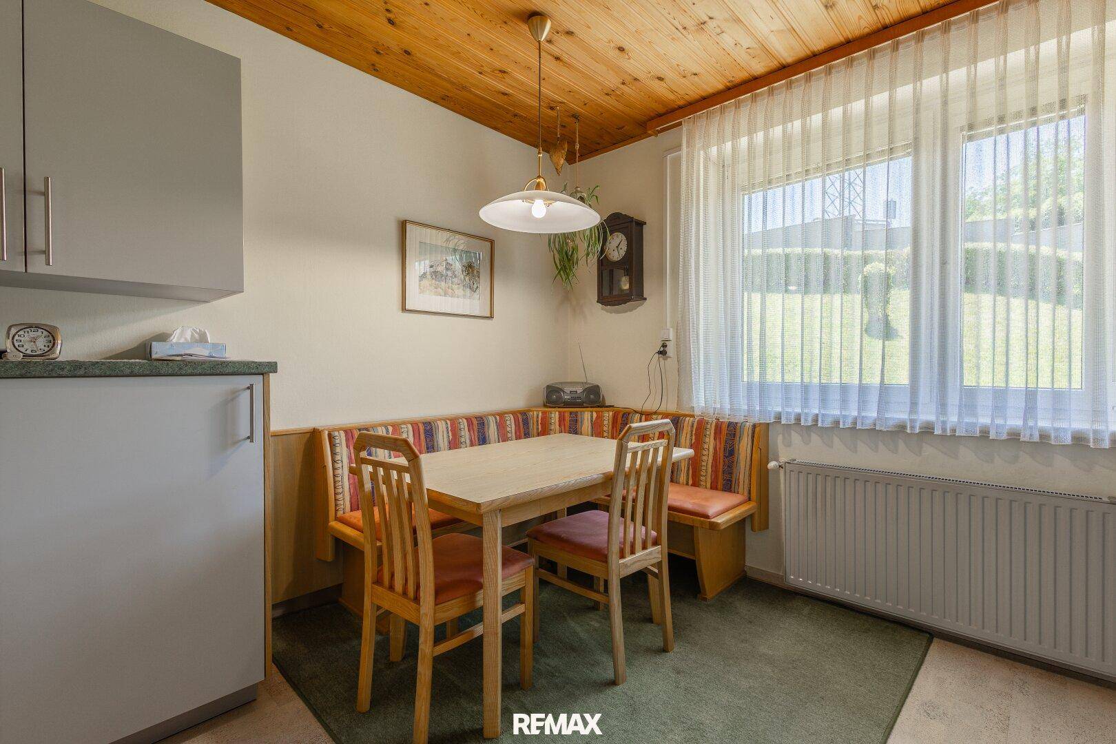 Gemütlicher Essbereich in der Küche mit Eckbank, Holztisch und Blick ins Grüne.