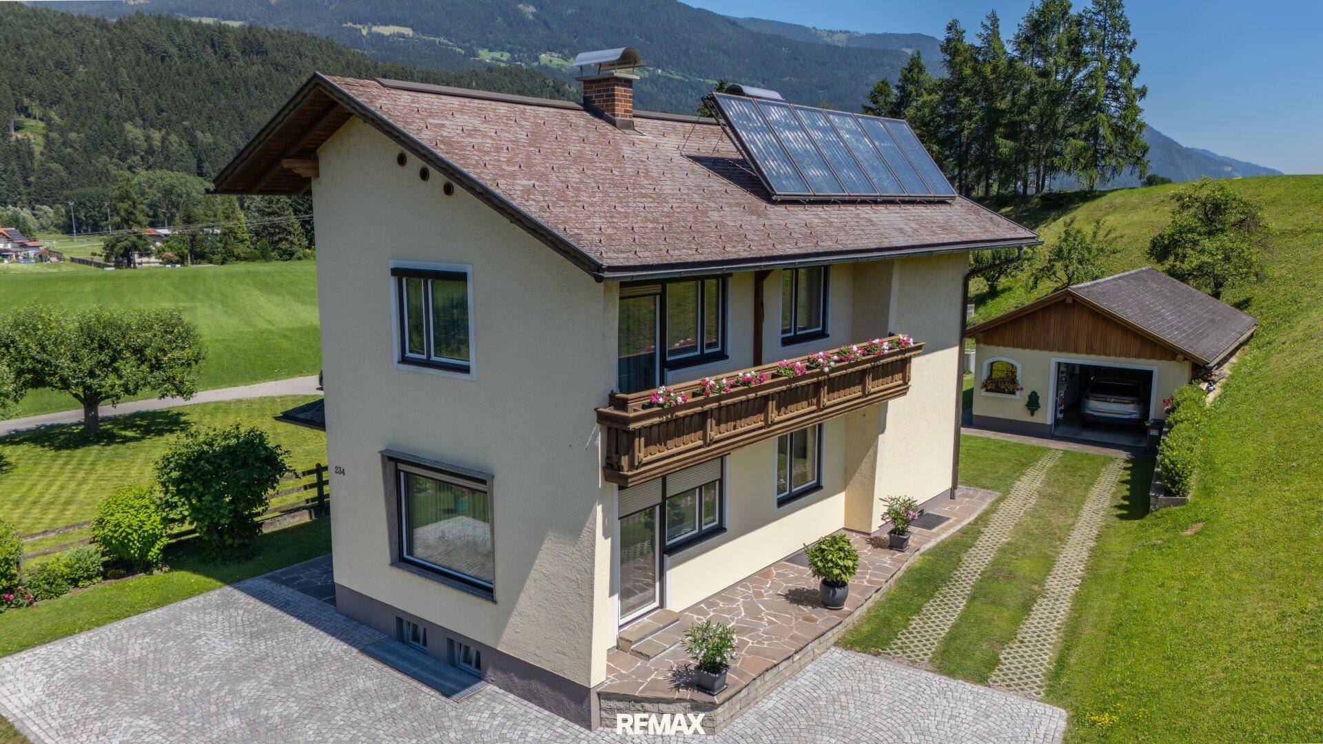 Ansicht des Hauses mit Solaranlage auf dem Dach, Balkon und gepflegter Außenanlage.