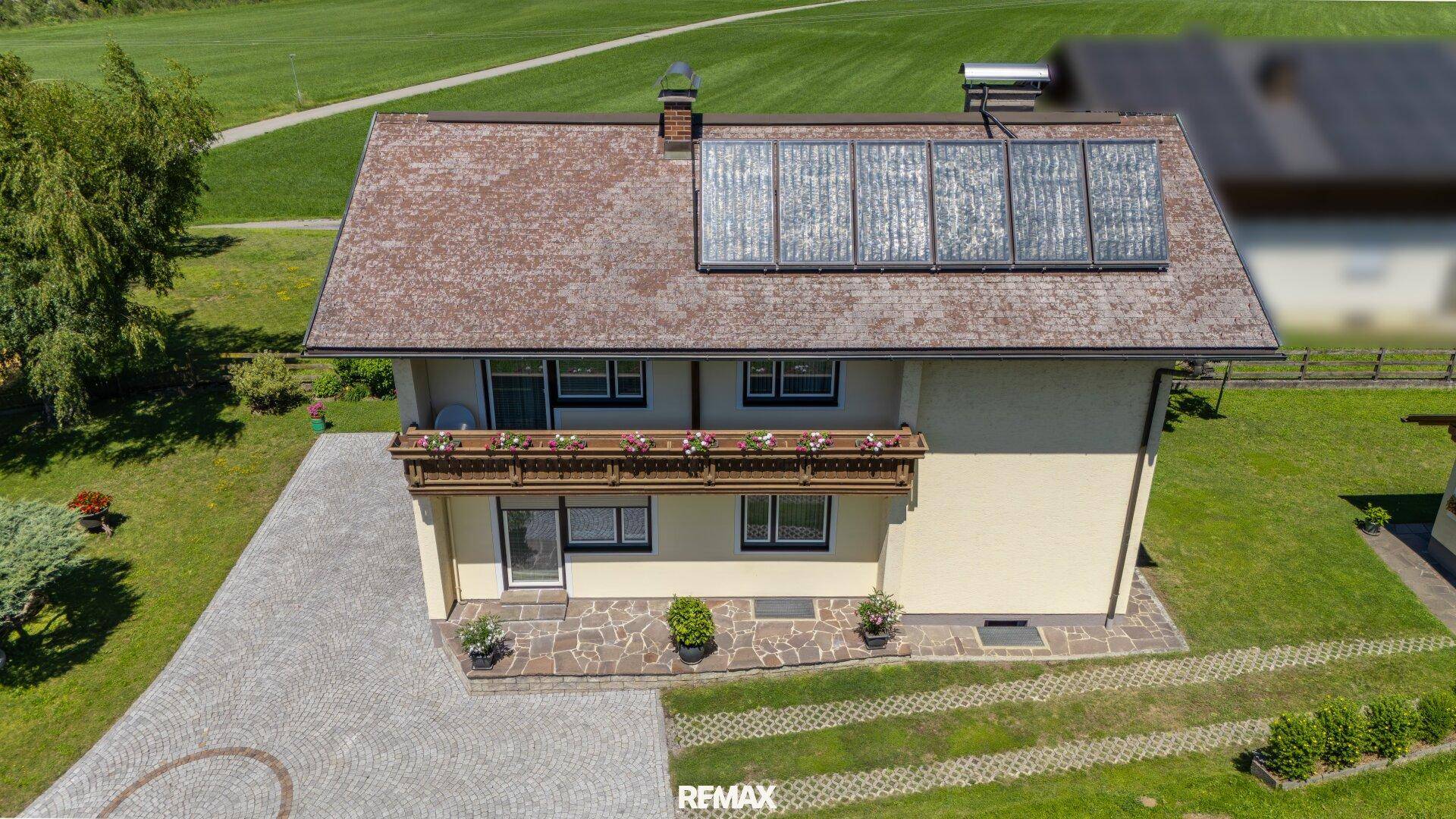 Vogelperspektive des Hauses mit Solaranlage, Balkon und weitläufigem Grundstück.