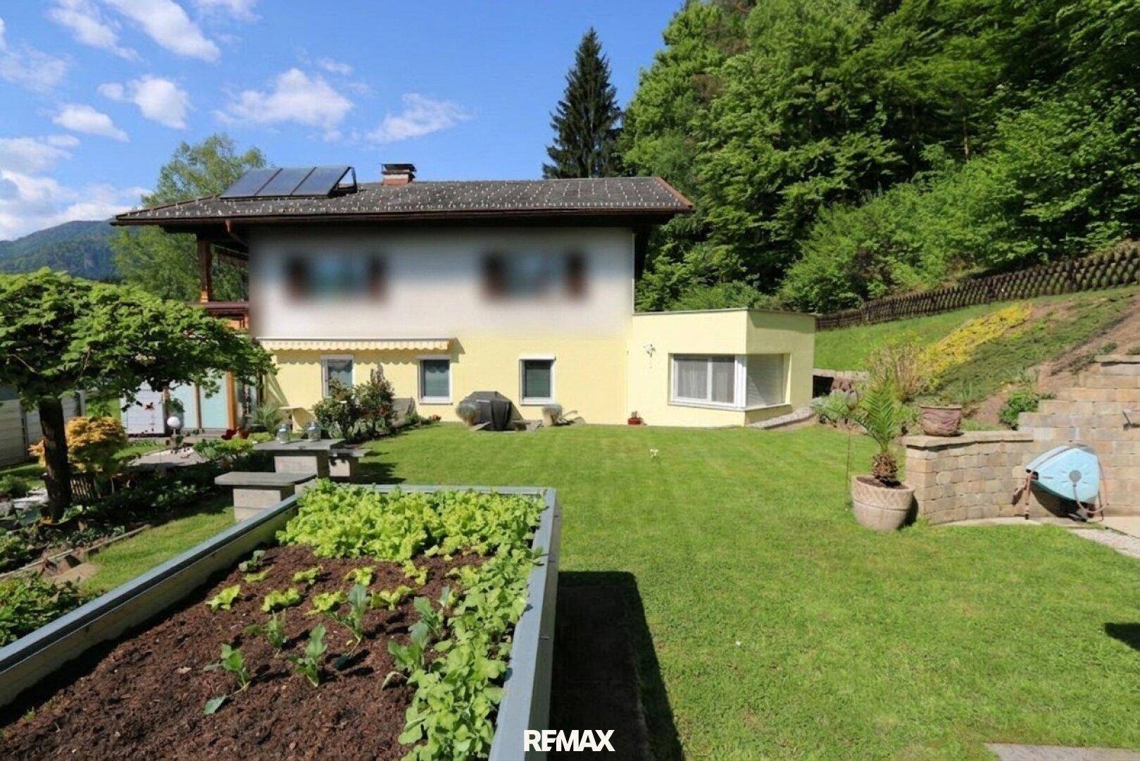 Weitläufiger Garten mit Hochbeet, Rasenfläche und Blick auf das Wohnhaus.