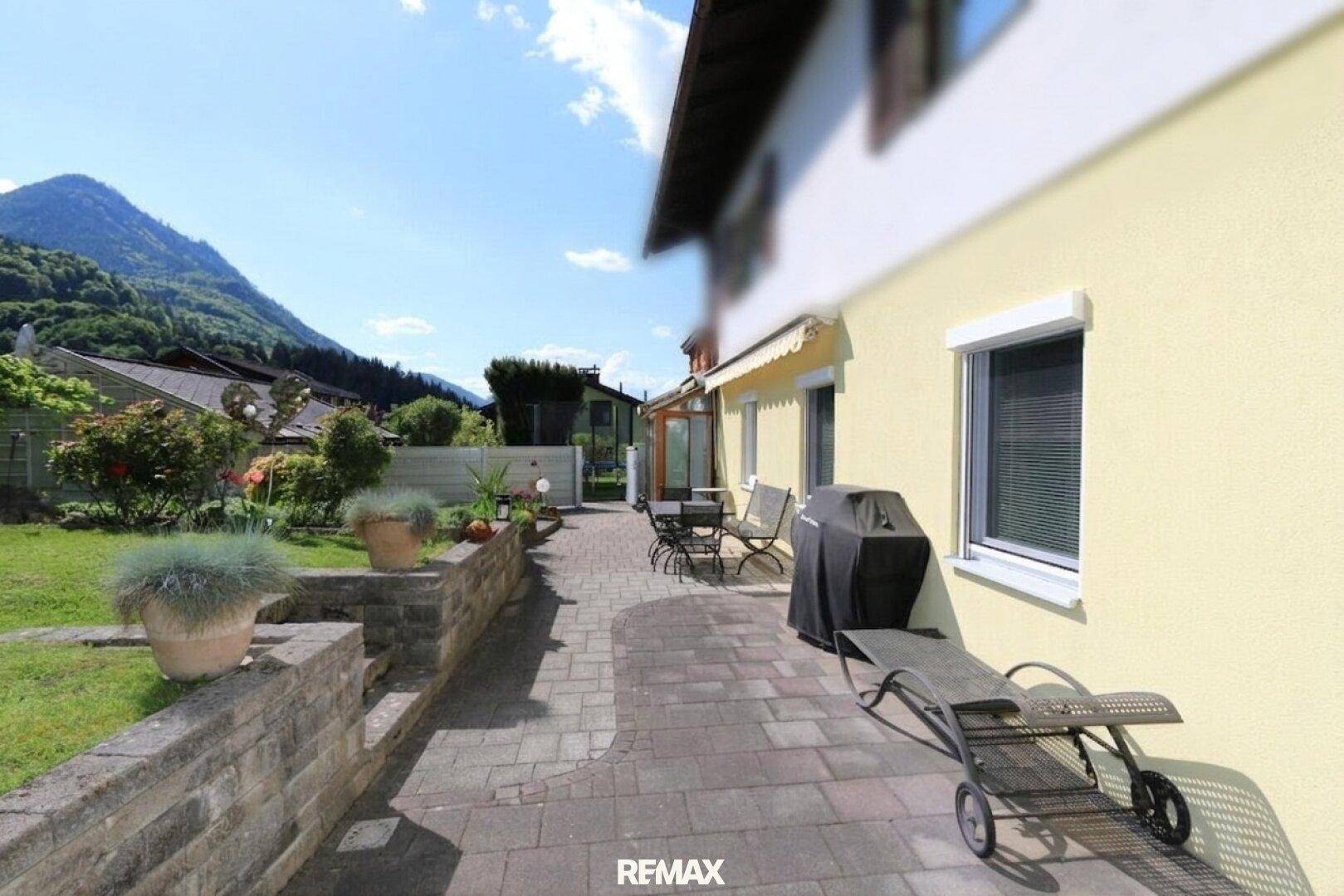 Geräumige gepflasterte Terrasse mit Grillbereich und Liegestuhl, ideal zum Entspannen im Freien.