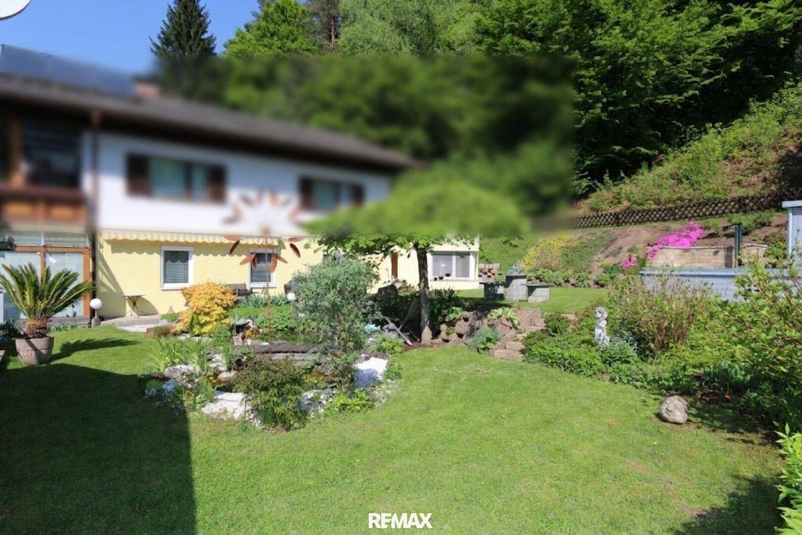 Großer, gepflegter Garten mit Rasenfläche, einem kleinen Teich und üppiger Bepflanzung.