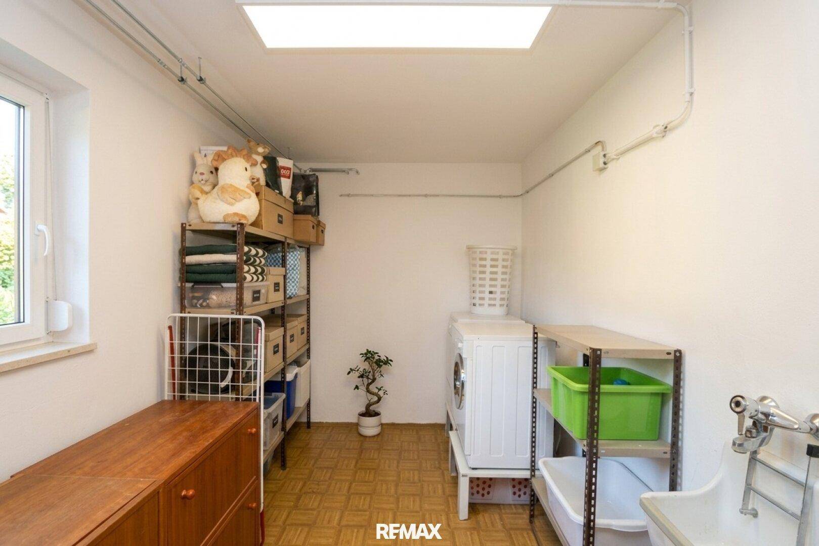 Hauswirtschaftsraum mit Waschmaschine, Regalen und Fenster für gute Belüftung.