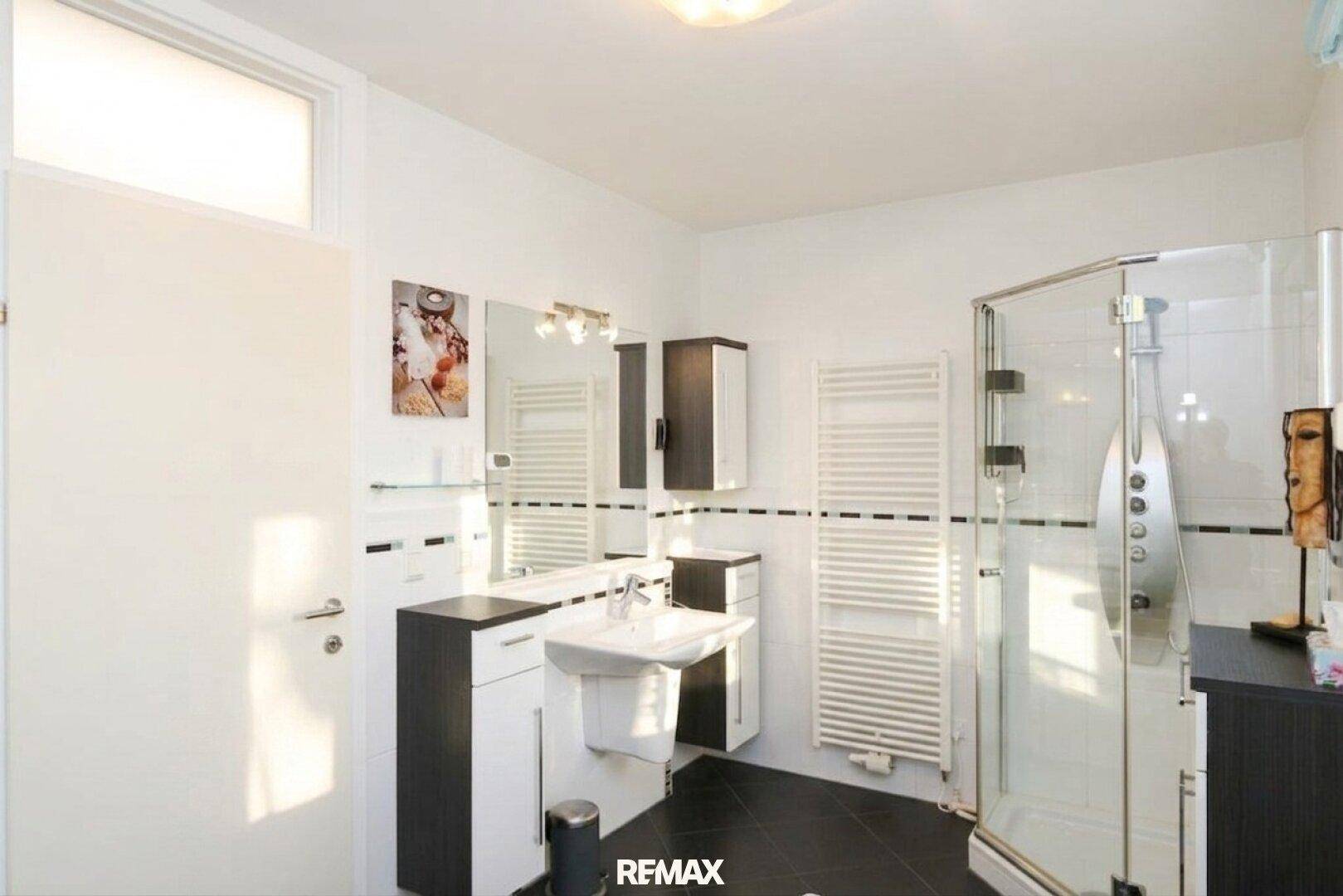 Modernes Badezimmer mit Duschkabine, Einzelwaschbecken und praktischem beheiztem Handtuchhalter.