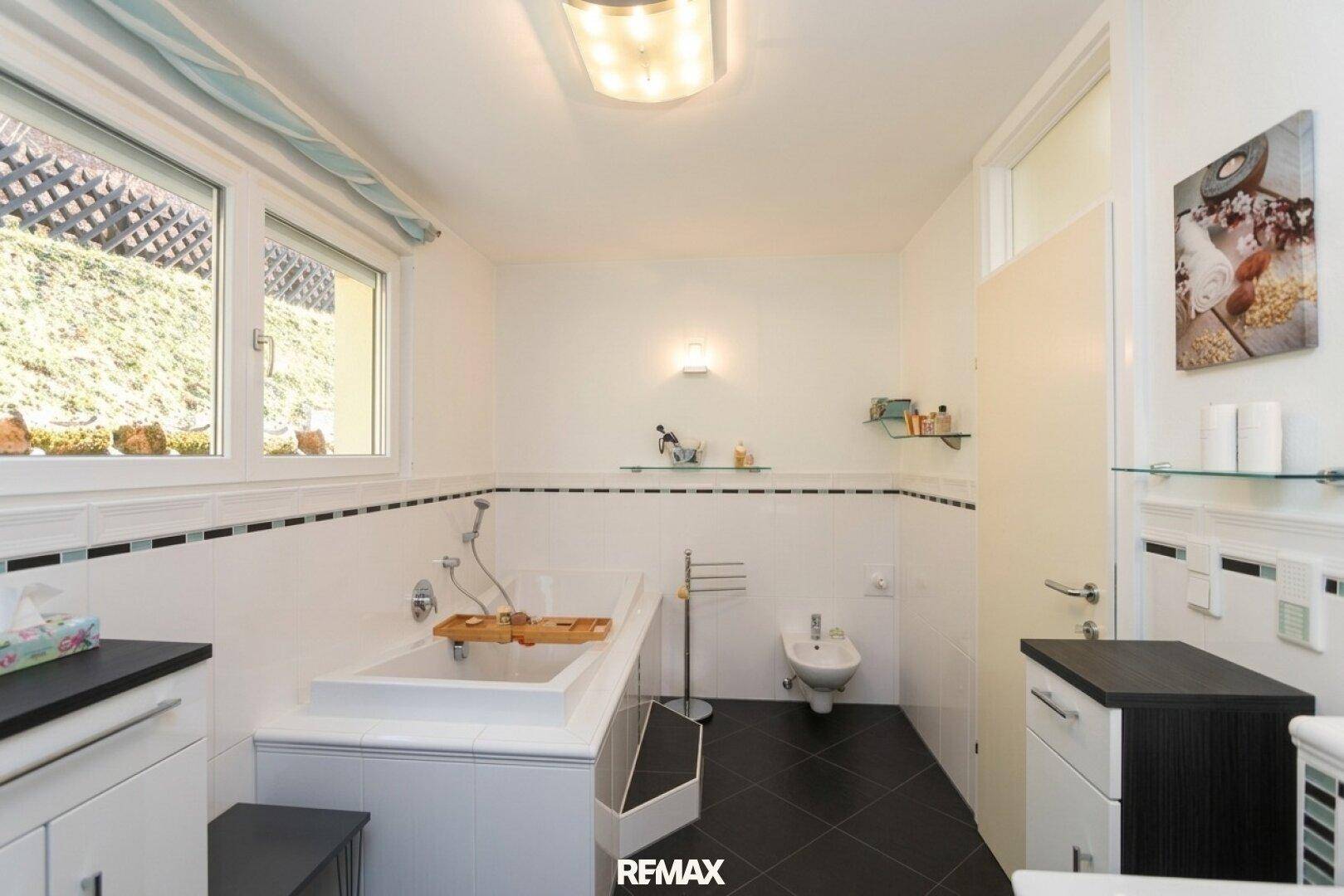 Geräumiges Badezimmer mit Badewanne, Bidet und Fenster für natürliches Tageslicht.