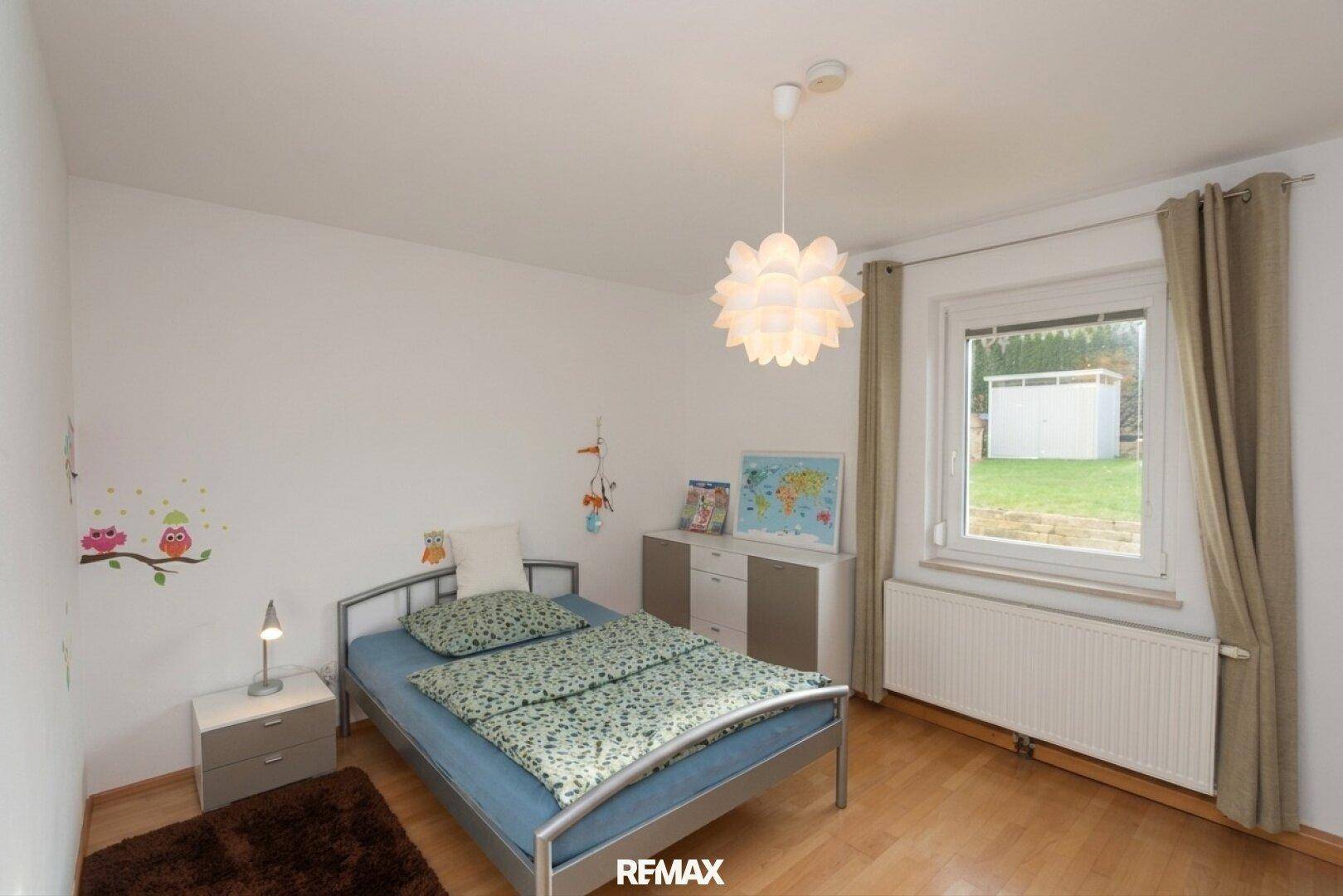 Kinderzimmer mit Holzboden, Fenster und einfacher, freundlicher Einrichtung.