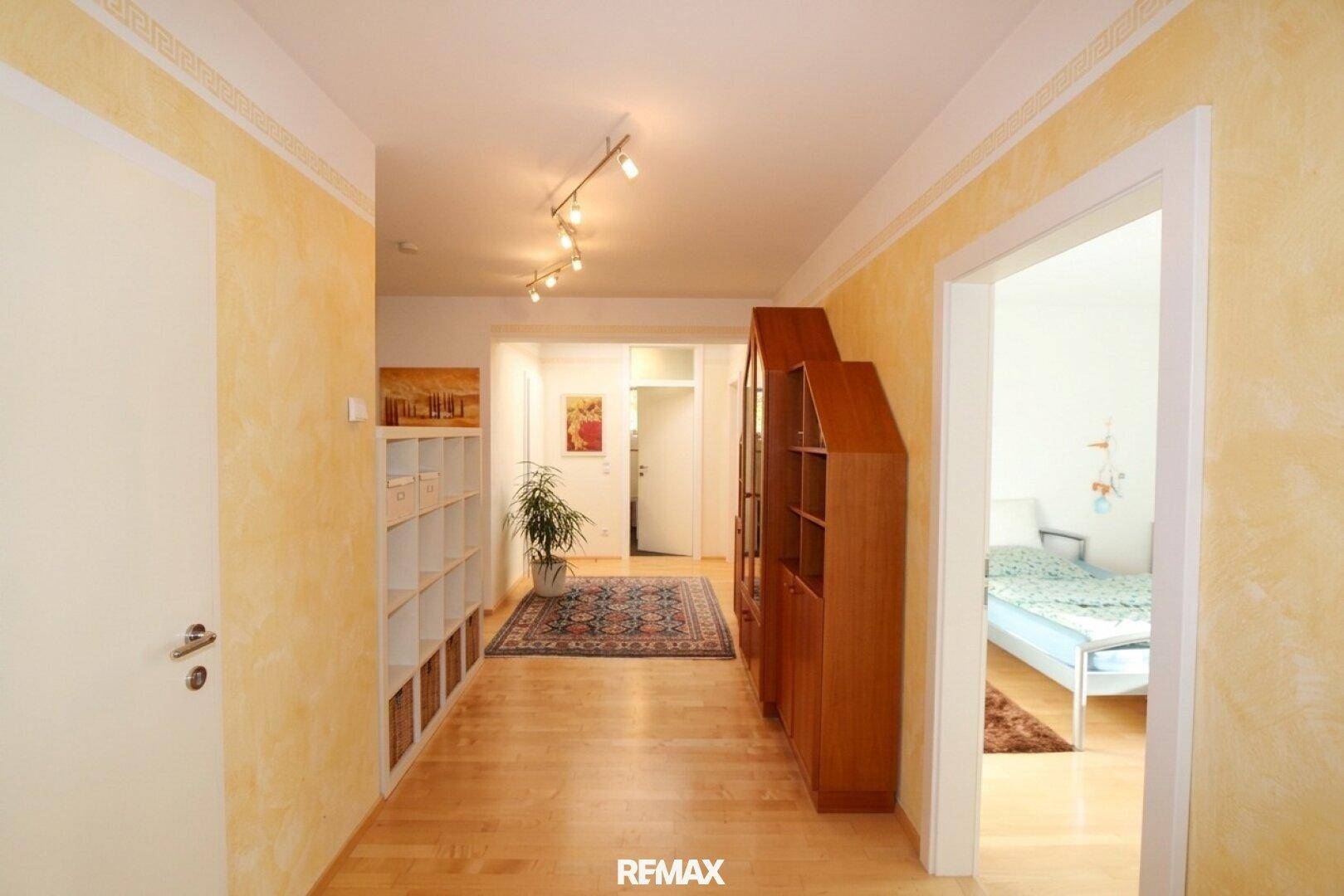 Geräumiger Flur mit Holzboden, gelben Wänden und Blick in angrenzende Zimmer.