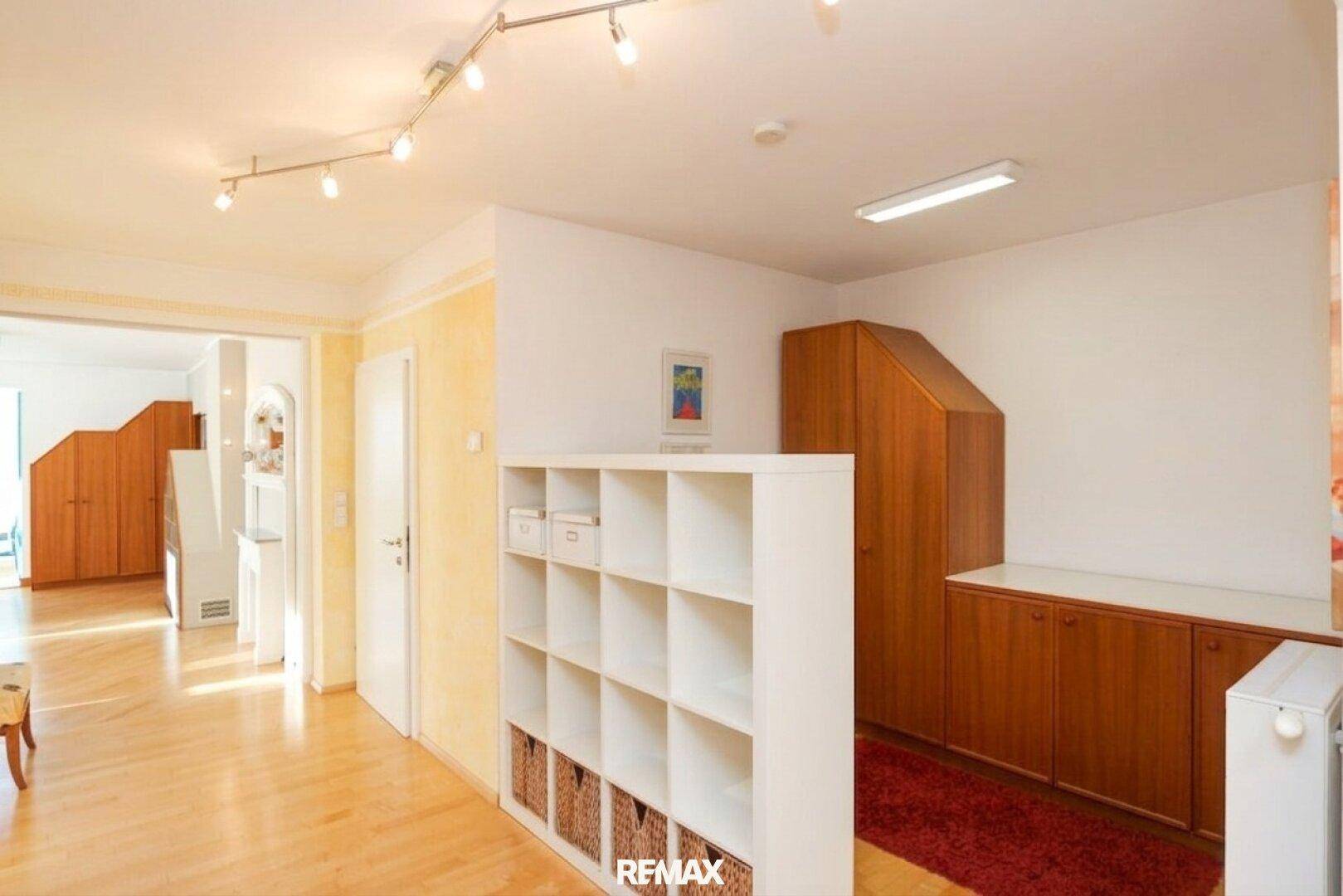 Heller Flur mit Holzboden, Regalen und Zugang zu mehreren weiteren Räumen.