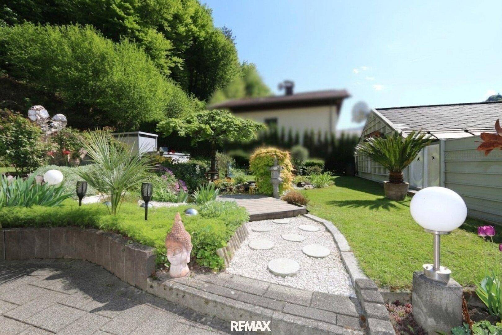 Gepflegter Garten mit Kiesweg, dekorativen Pflanzen und stimmungsvoller Gartenbeleuchtung.