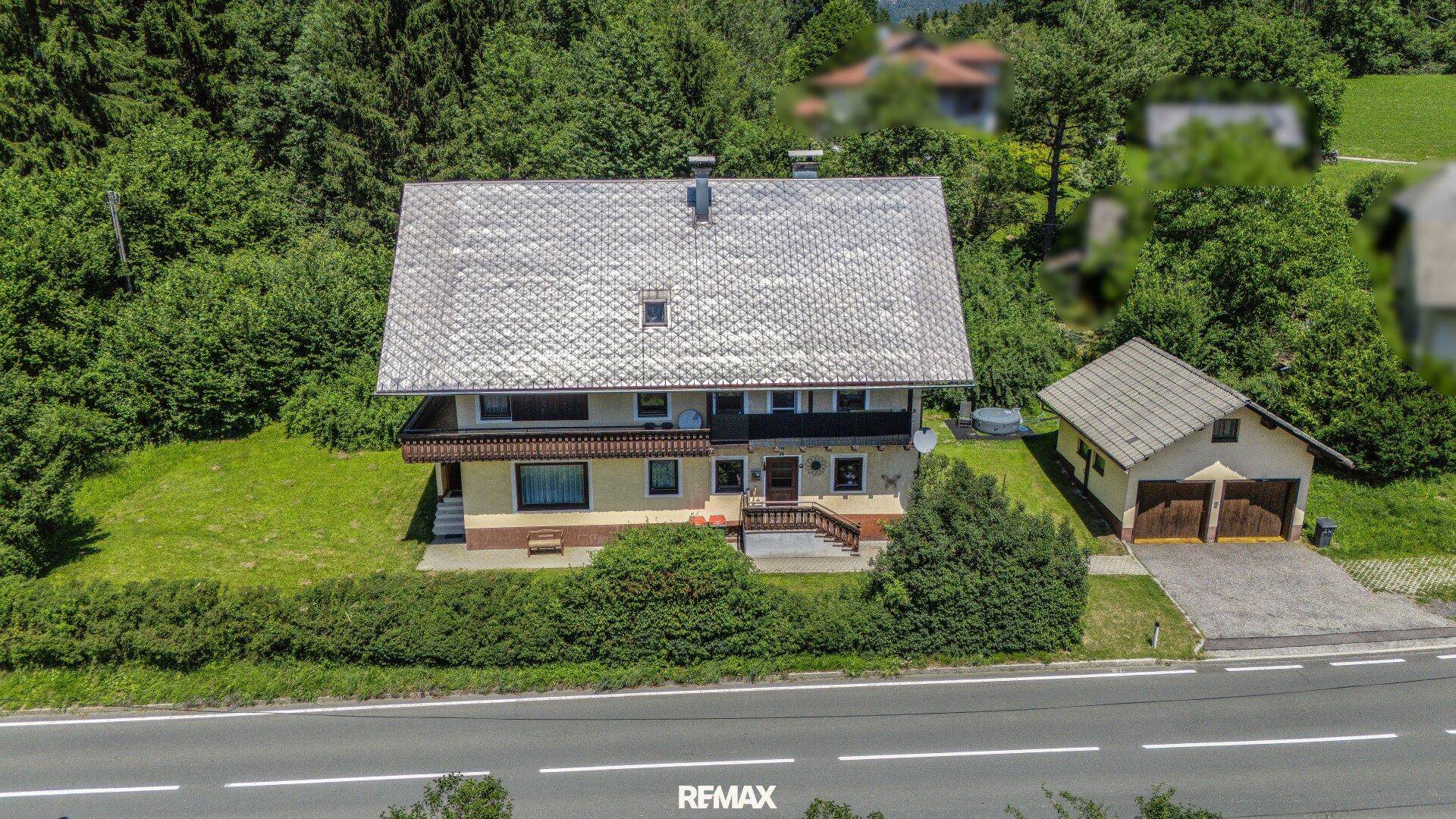 Vogelperspektive des Wohnhauses mit angrenzender Garage und gepflegtem Gartenbereich, umgeben von Natur.