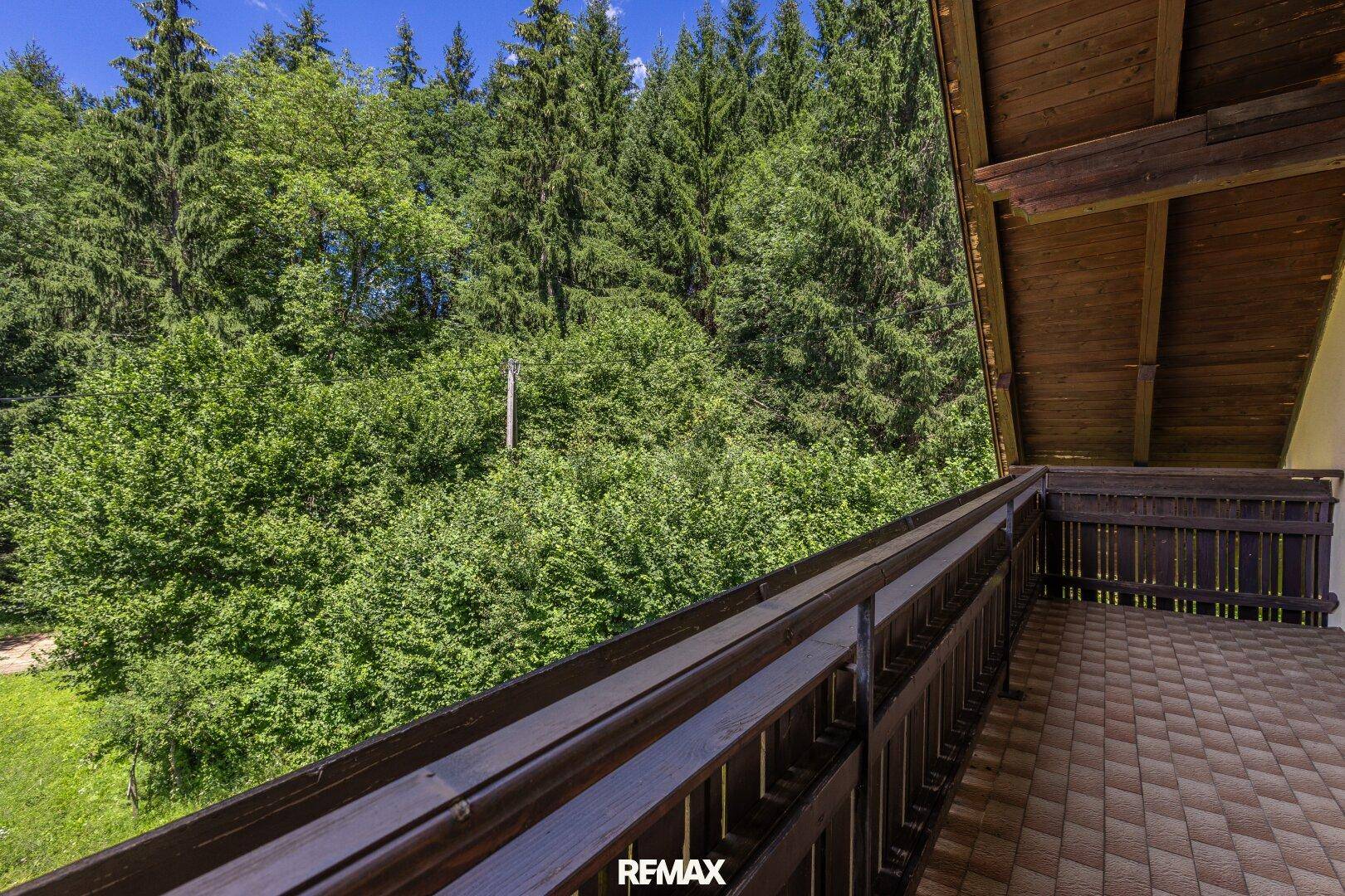 Langer Balkon mit Holzbalkon und Blick auf die umliegenden Wälder.