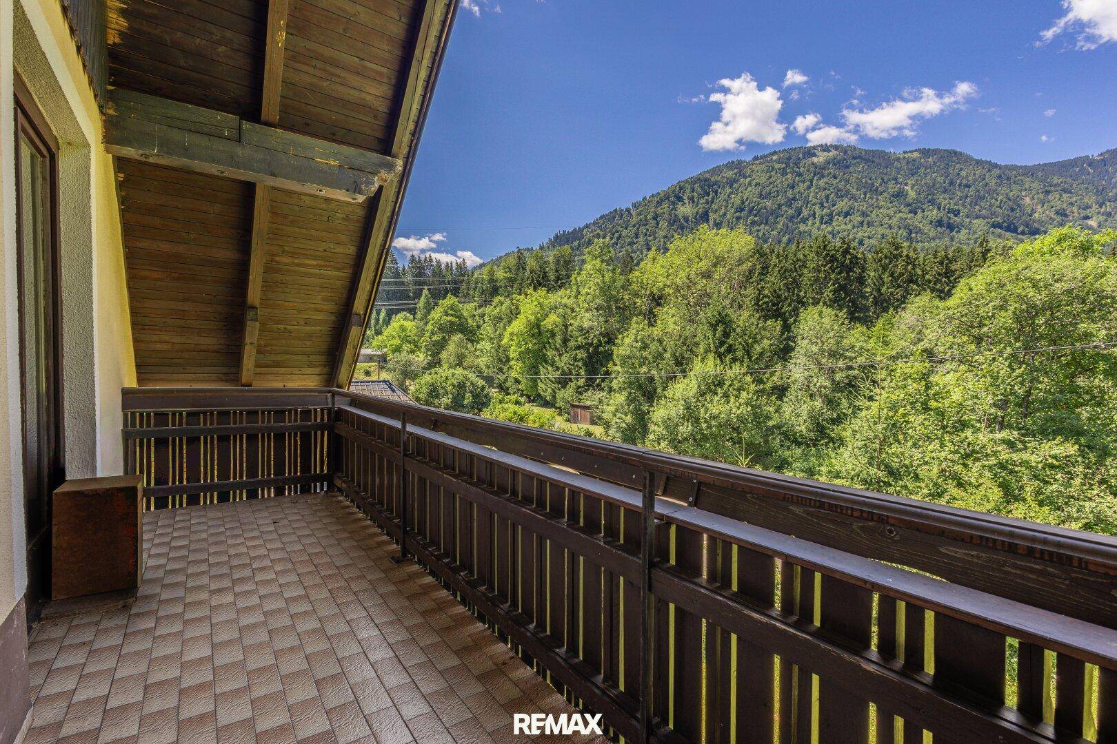Langer Balkon mit Holzbalkon und weitem Blick auf die bewaldeten Berge.