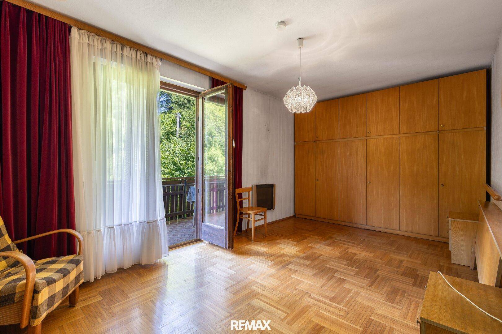 Geräumiges Schlafzimmer mit Parkettboden, Einbauschränken und Balkonzugang.