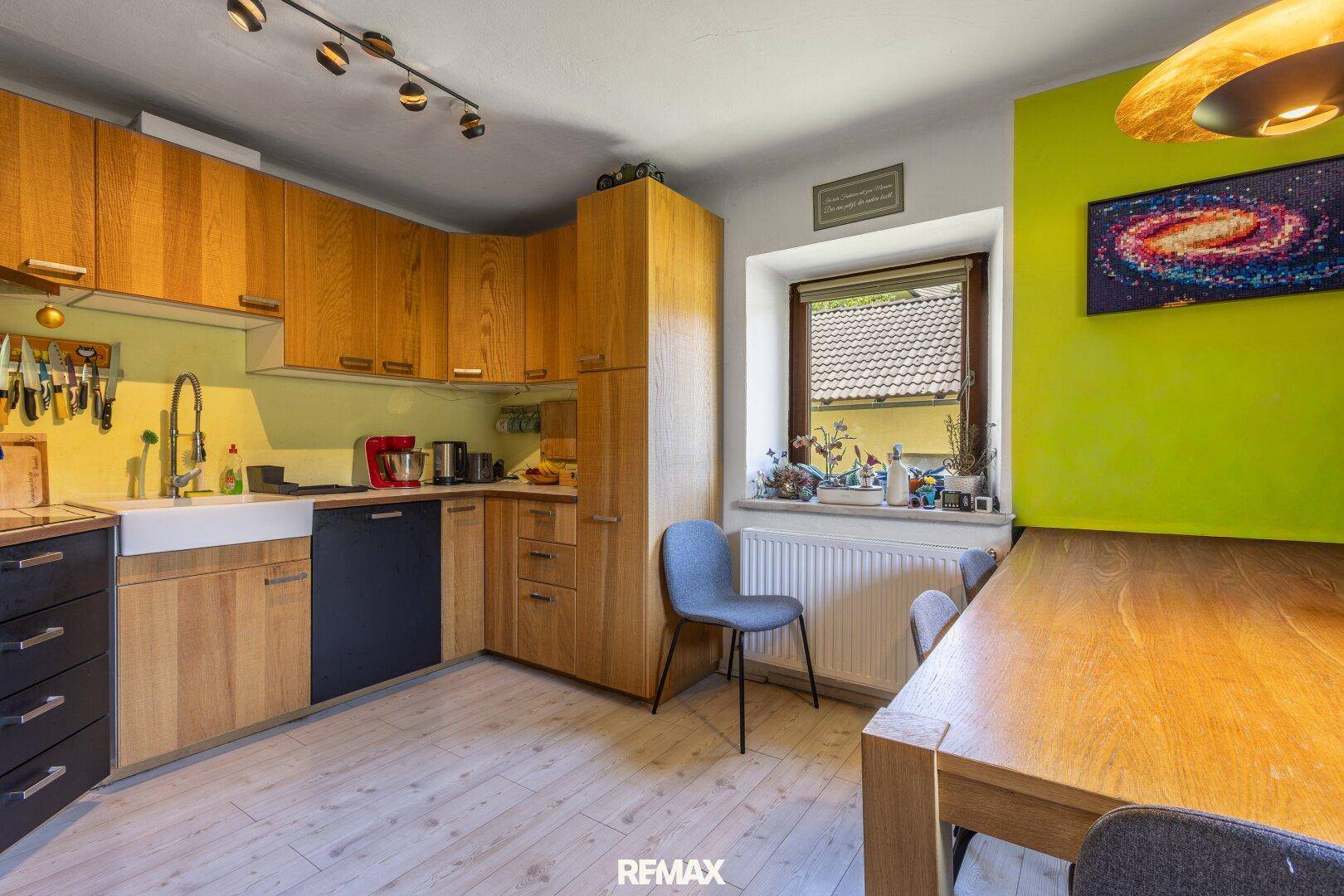 Moderne Küche mit Holzelementen, Essbereich und Blick ins Grüne.
