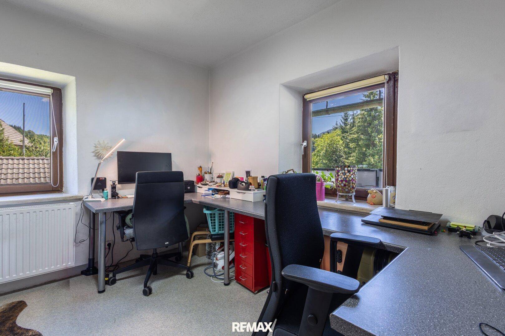 Funktionales Arbeitszimmer mit zwei Schreibtischen und Fenstern, die einen schönen Blick ins Grüne bieten.