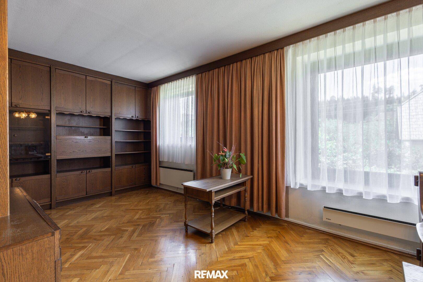 Geräumiges Wohnzimmer mit Parkettboden, großen Fenstern und Einbauschränken.