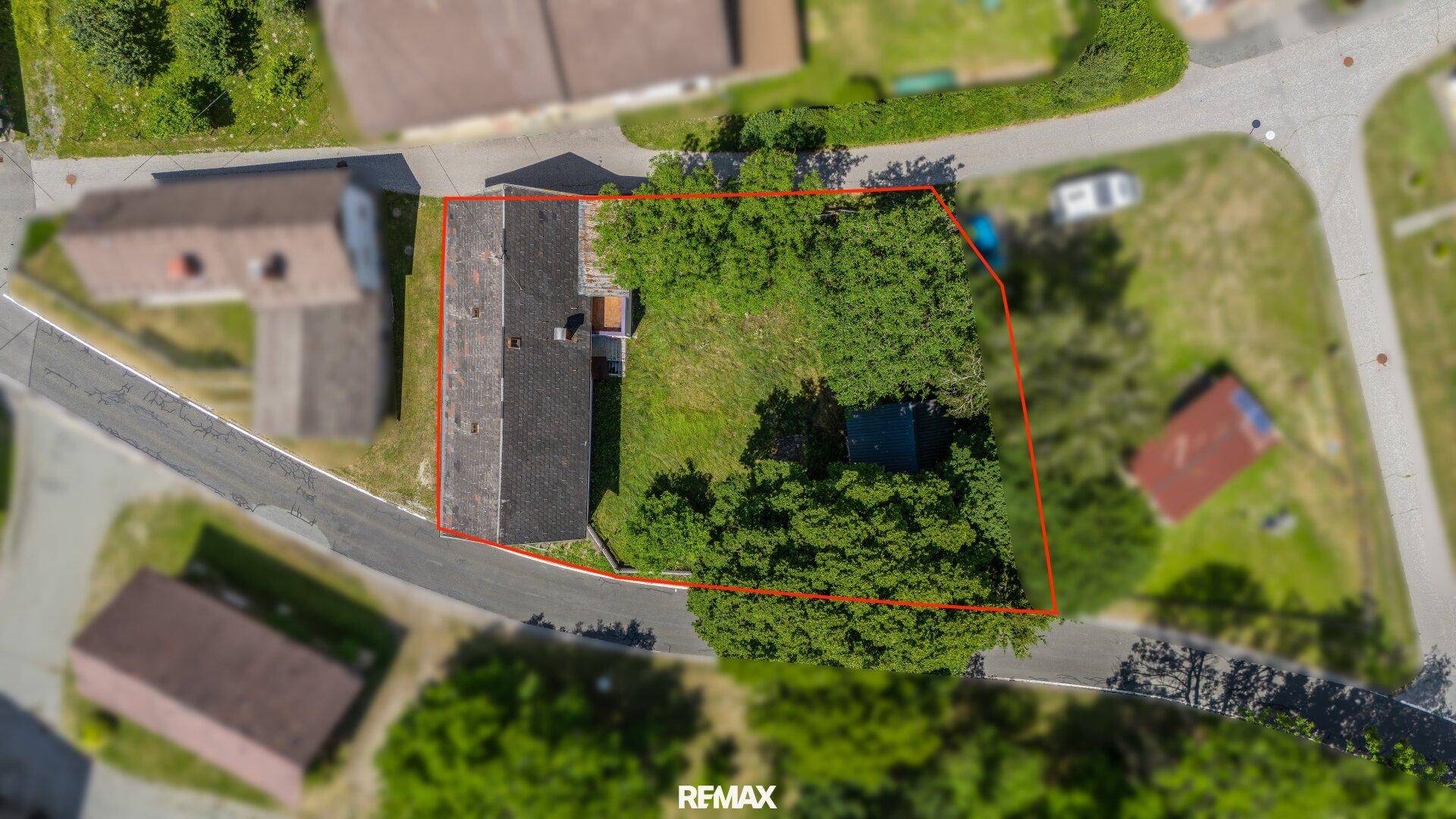 Luftaufnahme eines Grundstücks mit Haus und viel Grünfläche, rot umrandet.