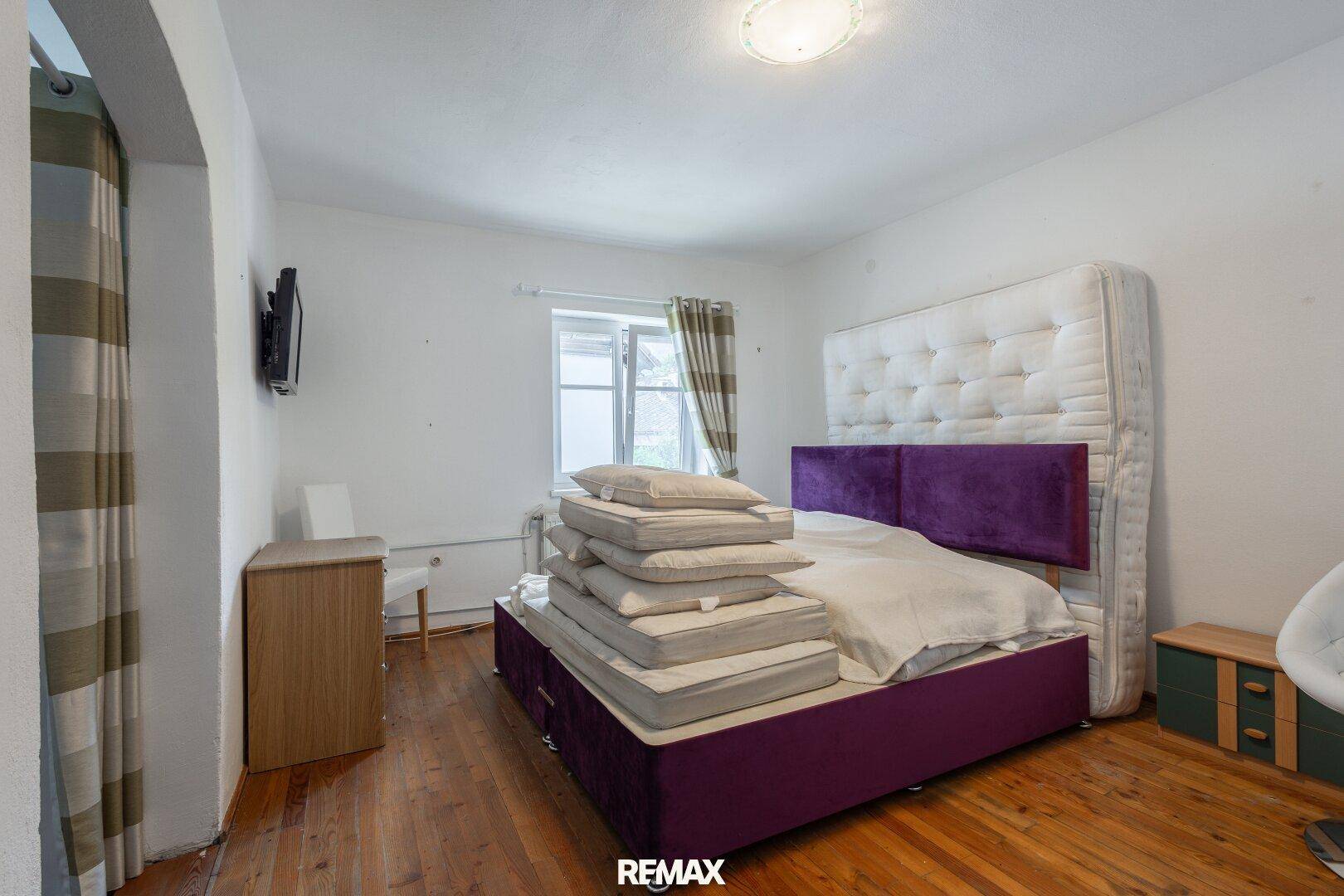 Geräumiges Schlafzimmer mit Holzboden, großem Bett und Fenster.
