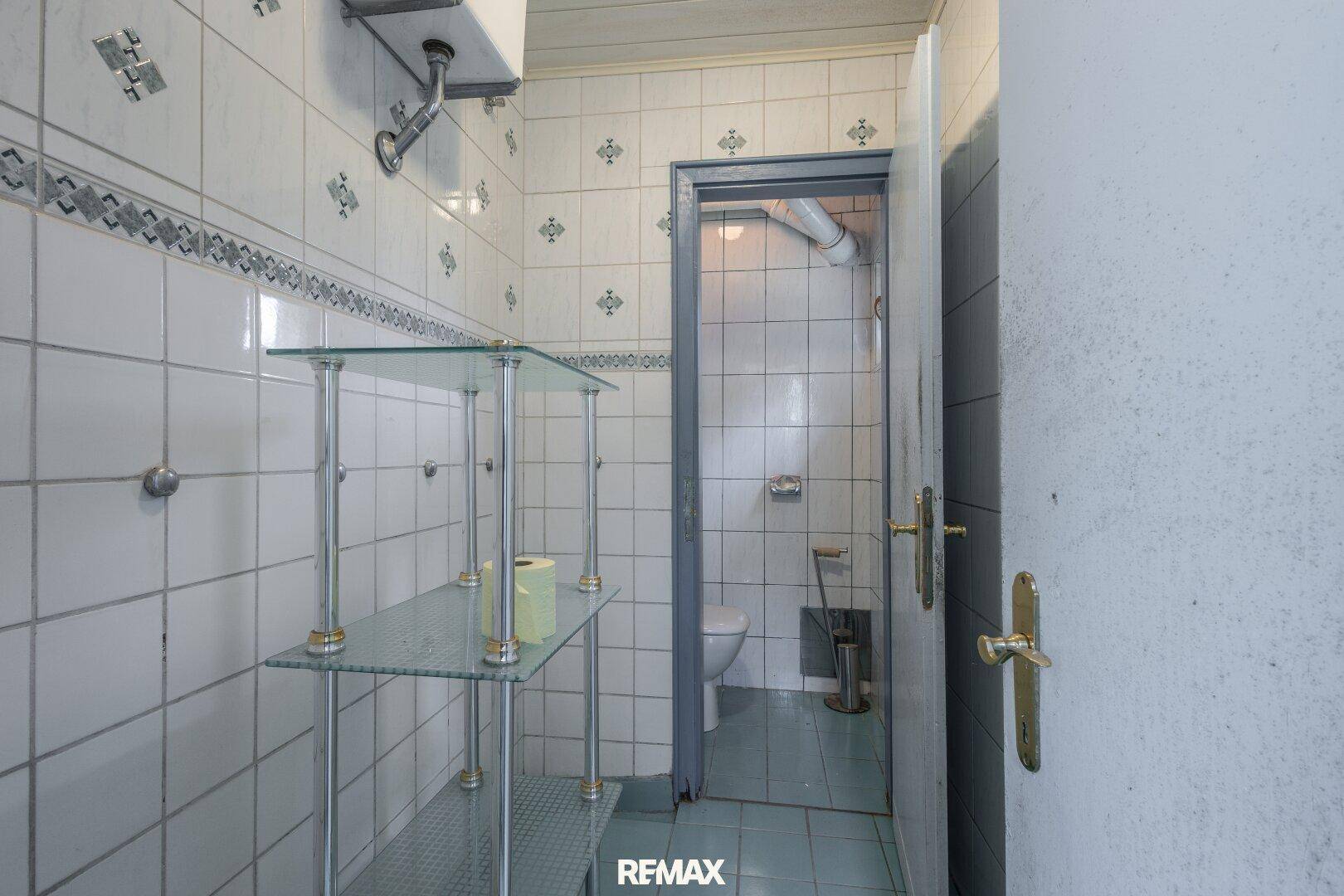Einfaches Badezimmer mit Fliesen und Blick auf die separate Toilette.