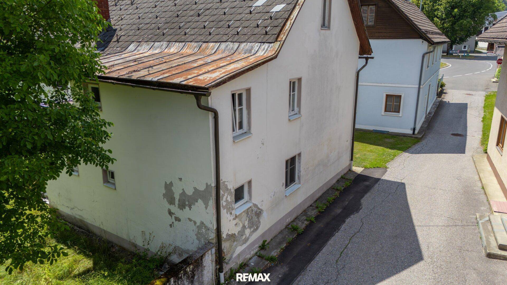 Rückansicht des weißen Hauses mit sichtbaren Gebrauchsspuren an der Fassade.
