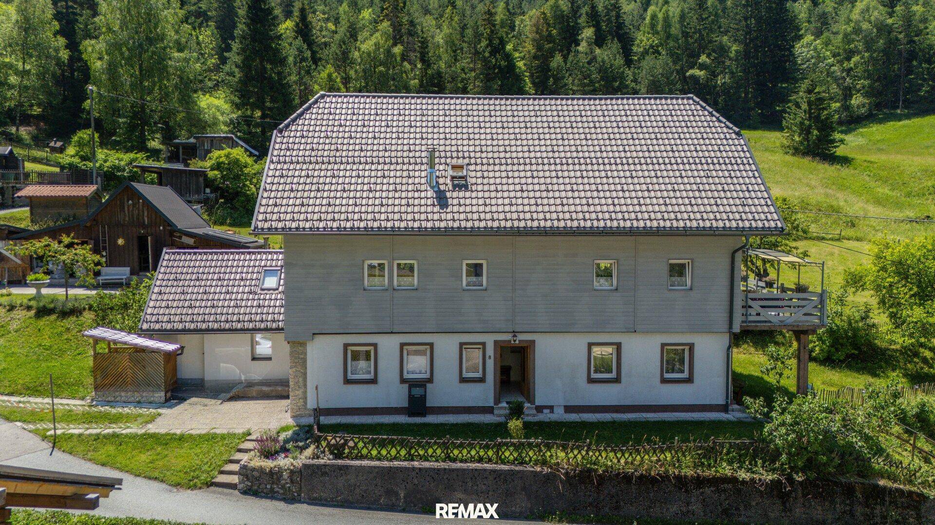 Vorderansicht eines Einfamilienhauses mit Holzfassade, Satteldach und gepflegtem Vorgarten.