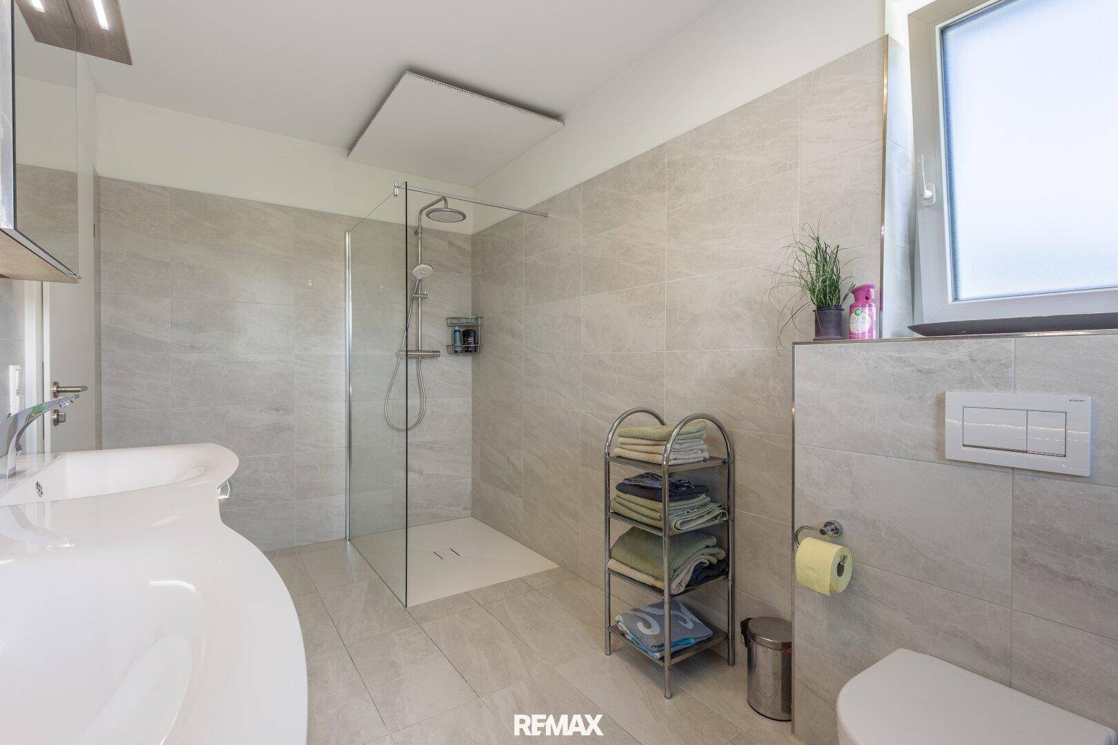 Modernes Badezimmer mit ebenerdiger Dusche, Fliesenboden und Fenster.