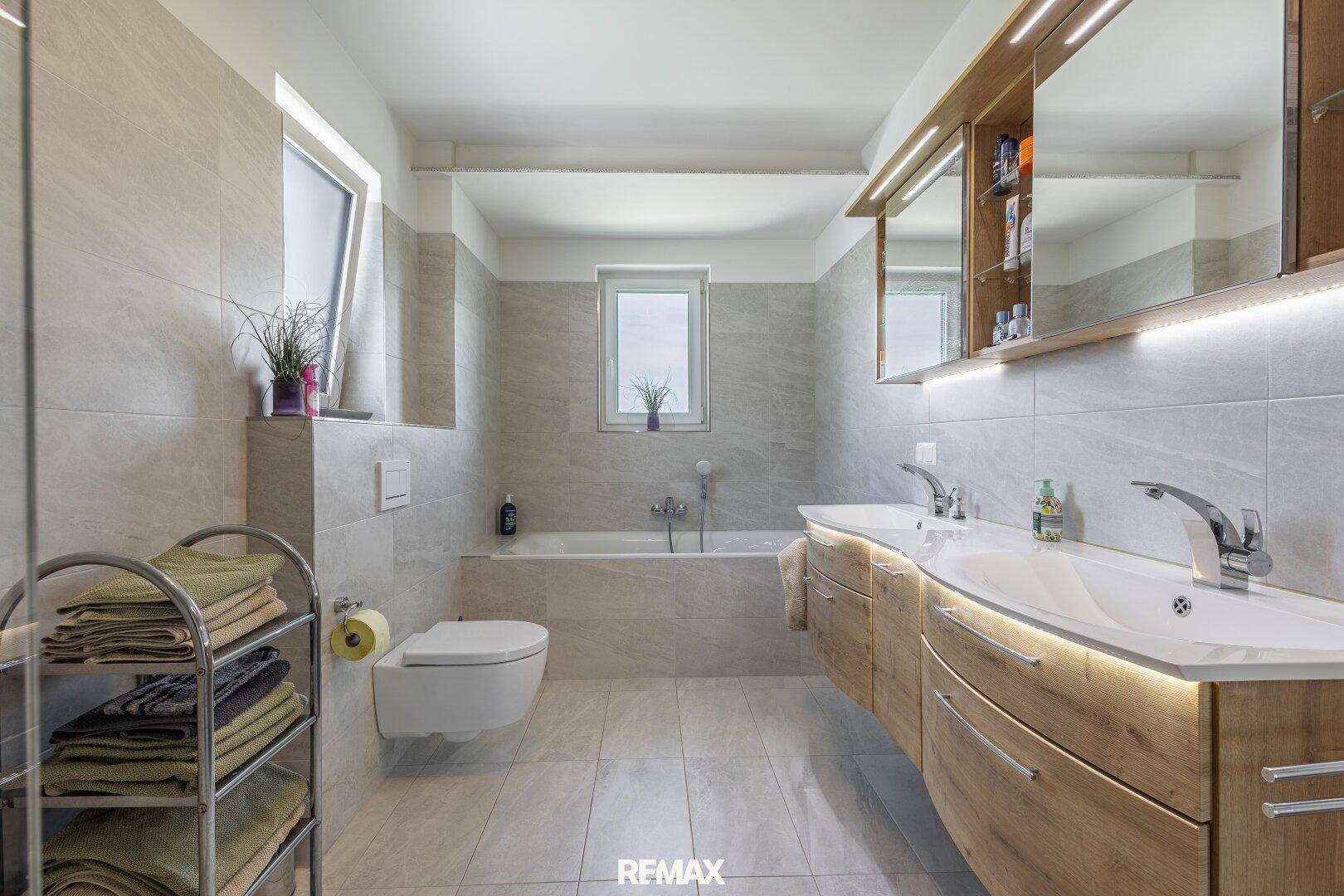 Großes modernes Badezimmer mit Doppelwaschbecken, Badewanne und Fenster.
