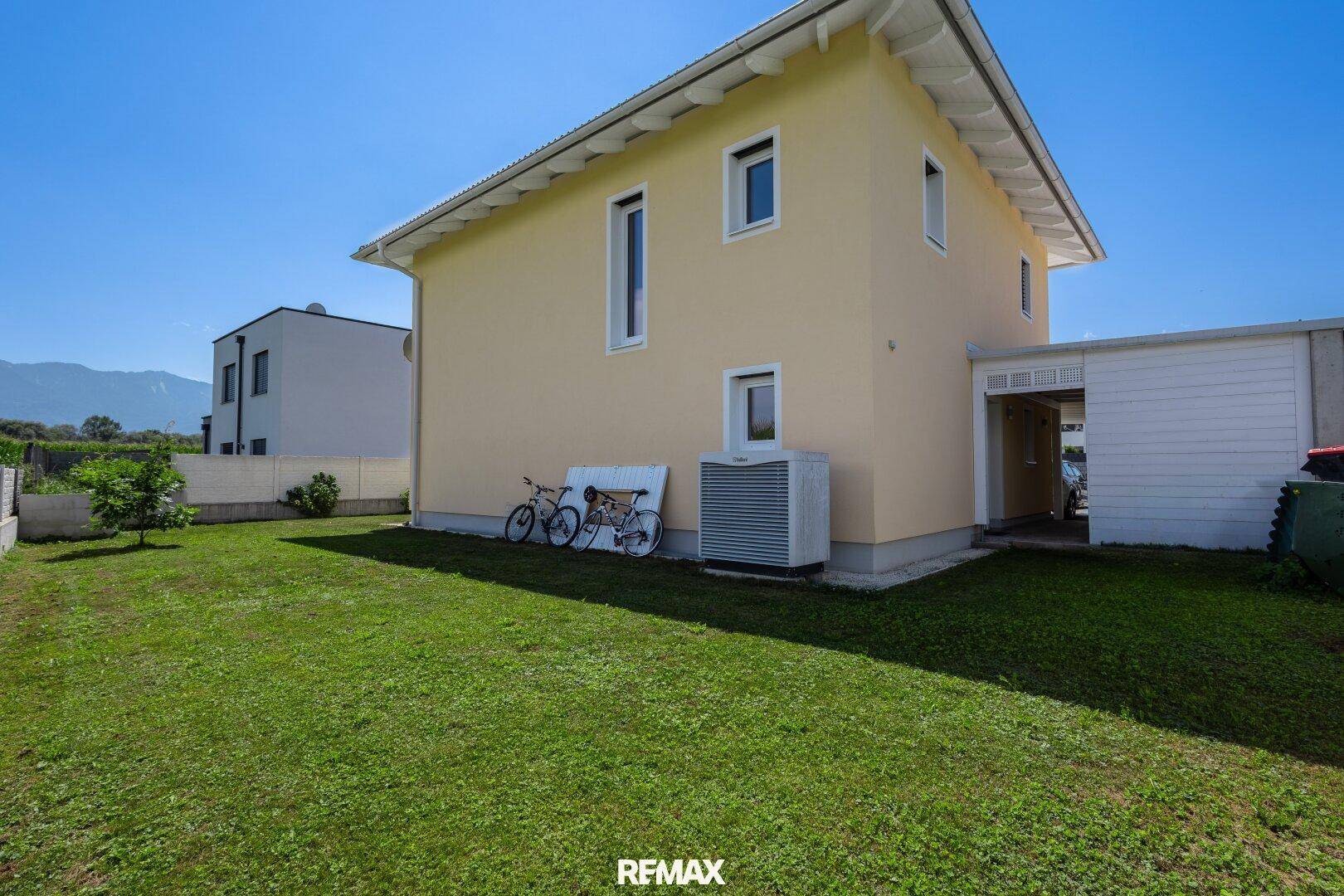 Seitenansicht des Hauses mit Rasenfläche und Klimaanlage.