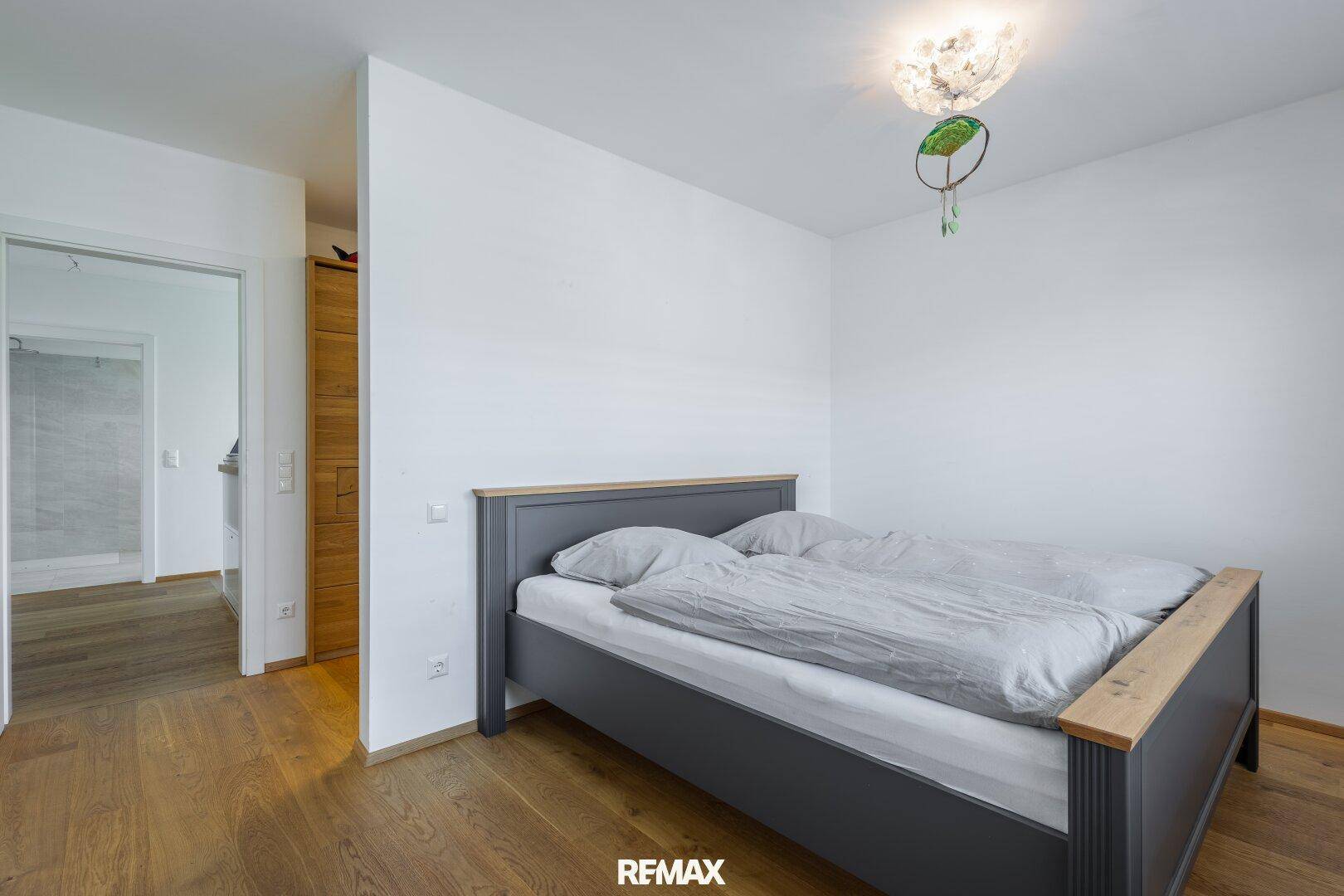 Schlafzimmer mit Holzboden und Zugang zu einem angrenzenden Badezimmer.