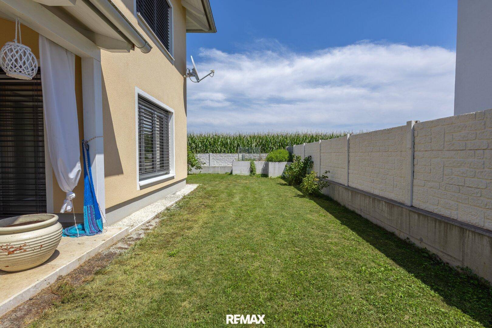 Seitenansicht des Hauses mit Zugang zum Garten und Blick auf das angrenzende Maisfeld.