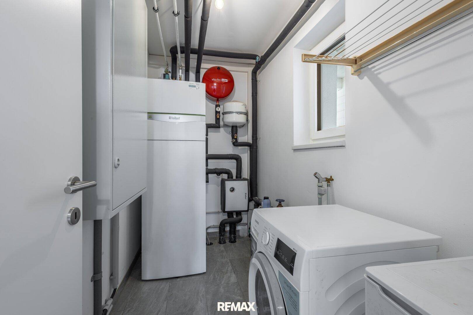 Praktischer Hauswirtschaftsraum mit Waschmaschine, Trockner und Heizungsanlage.