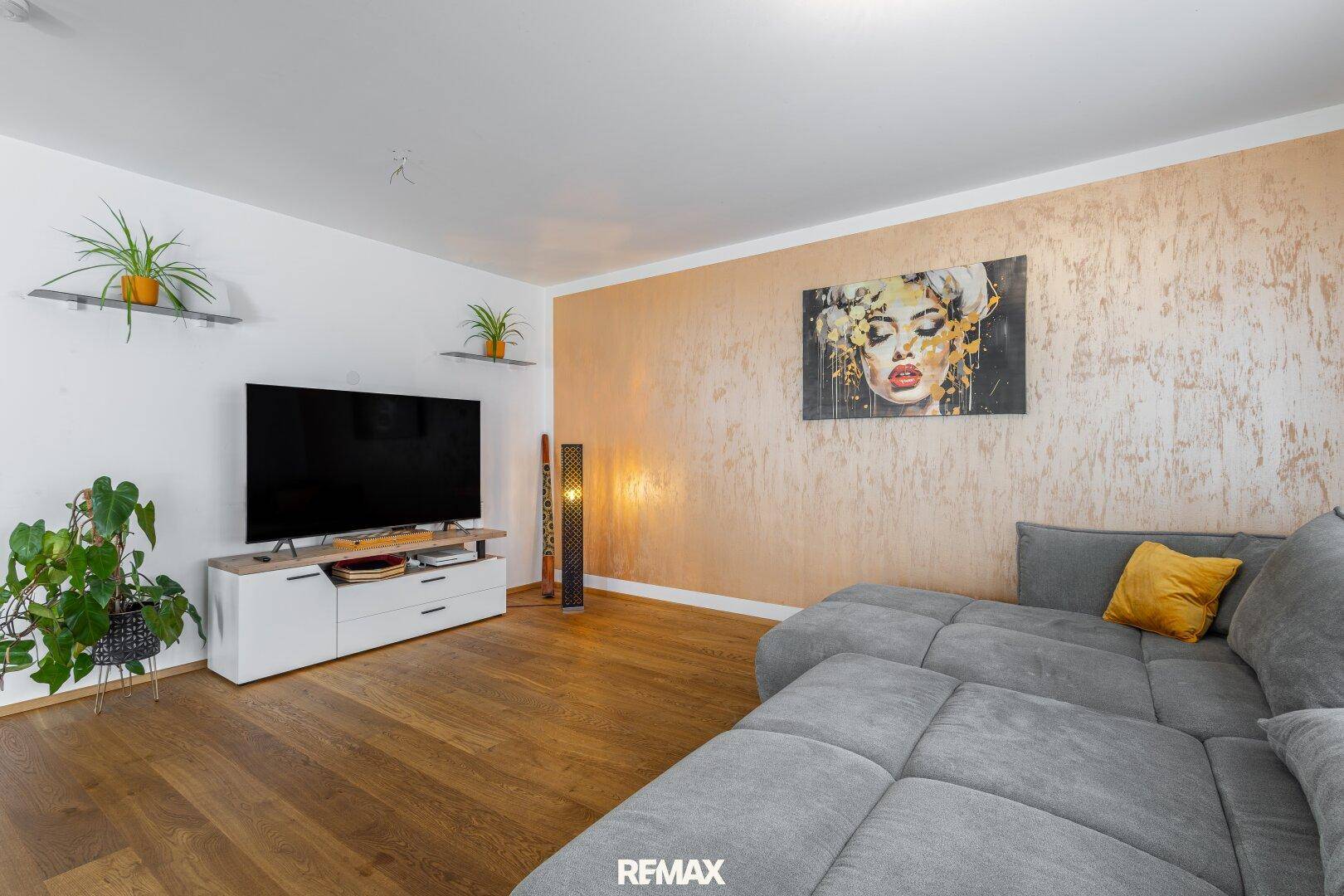 Gemütliches Wohnzimmer mit großem Ecksofa, Holzboden und dekorativer Wand.