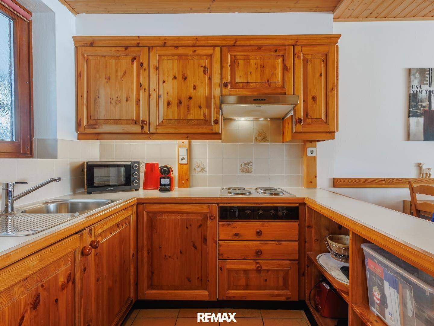 Funktionale Küche im Landhausstil mit Holzschränken, Elektroherd und integrierter Dunstabzugshaube.
