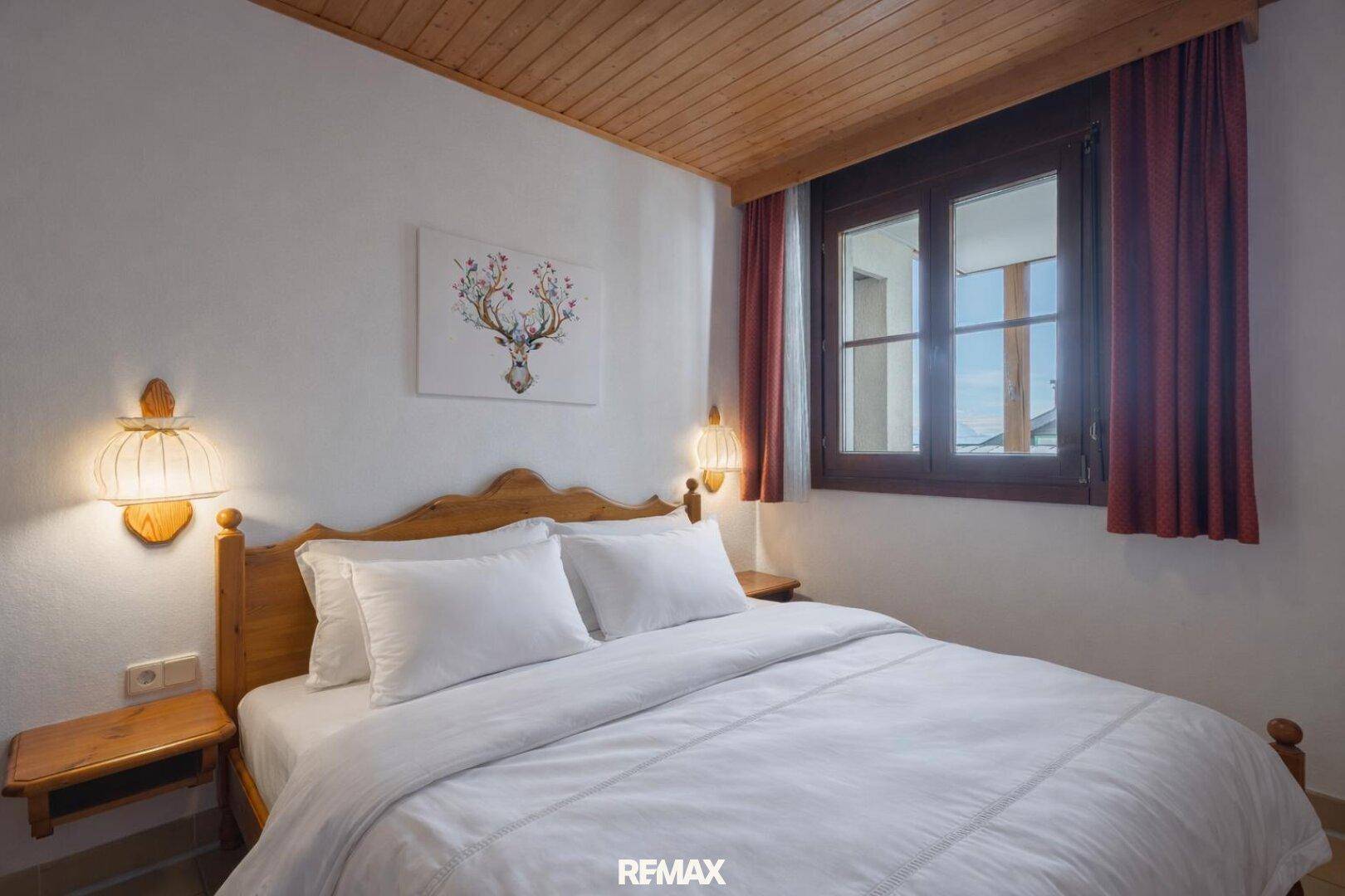 Gemütliches Schlafzimmer mit Doppelbett, Holzmöbeln und traditioneller Wandbeleuchtung.