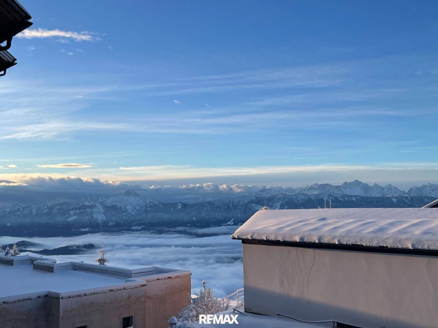 Atemberaubender Panoramablick auf schneebedeckte Berge und eine Wolkendecke über dem Tal.